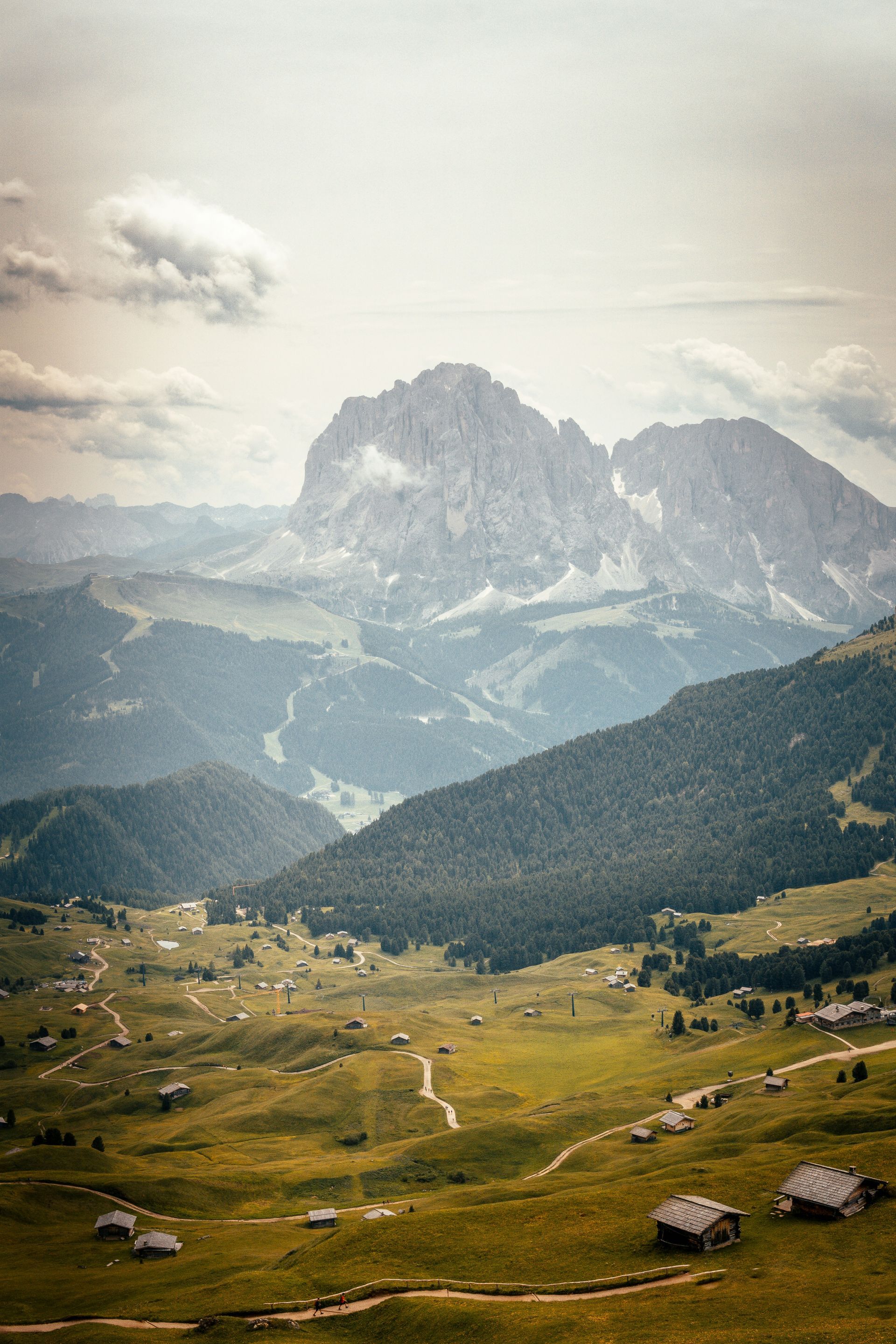 The Dolomites in the background, and a grassy field is in the foreground in Italy.