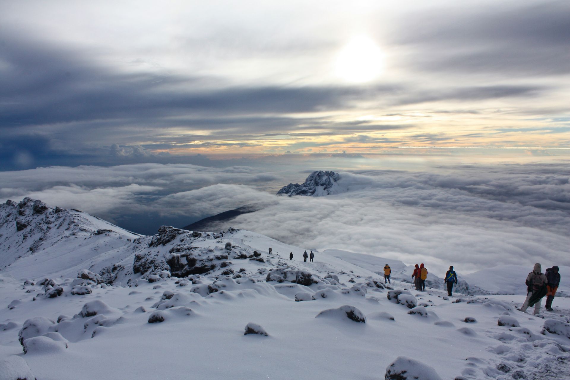 A group of people are standing on top of Mount Kilimanjaro, covered in snow in Tanzania.