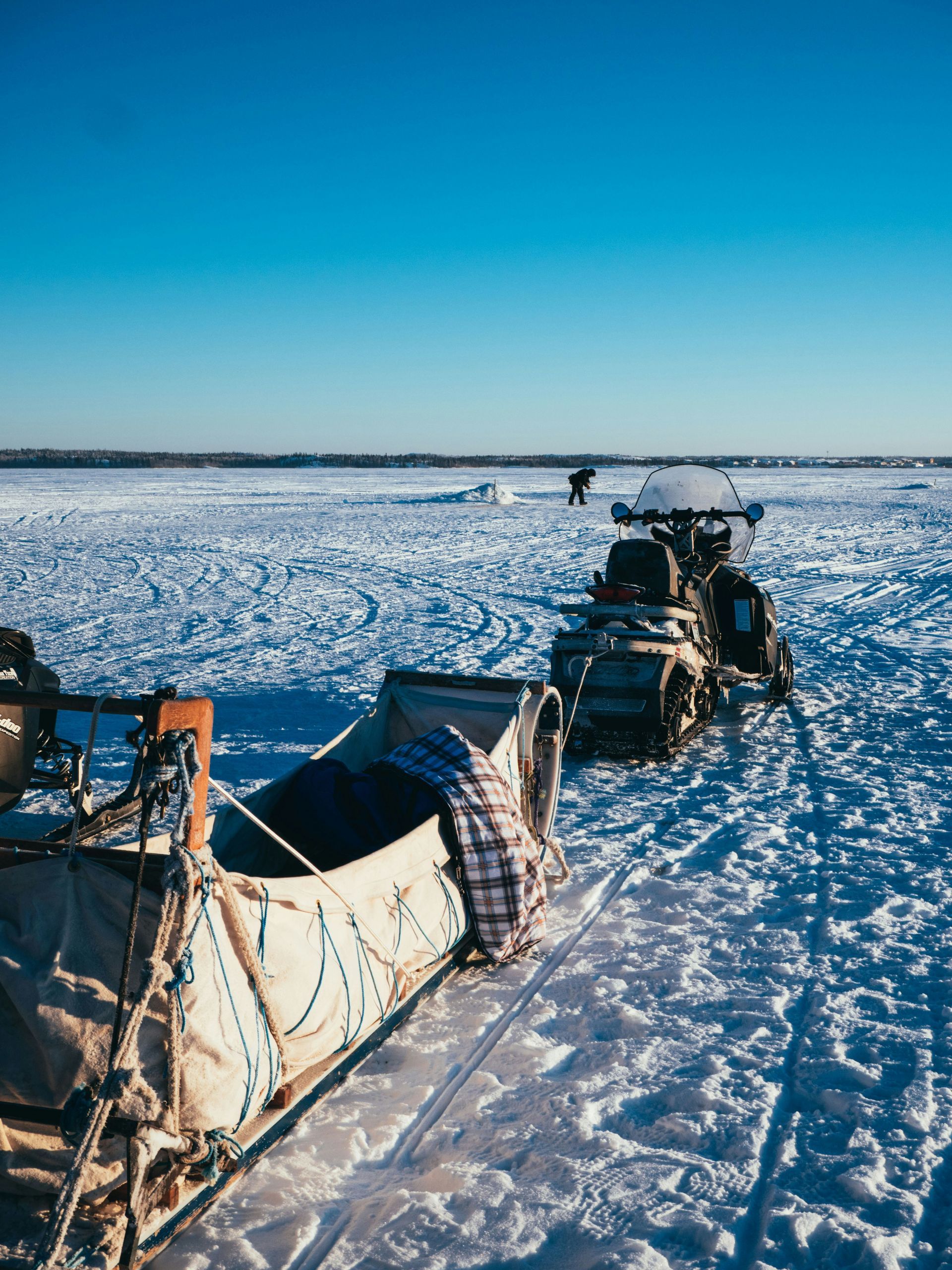 A snow-covered landscape with a snow tractor pulling a sled in Yellowknife, Canada.