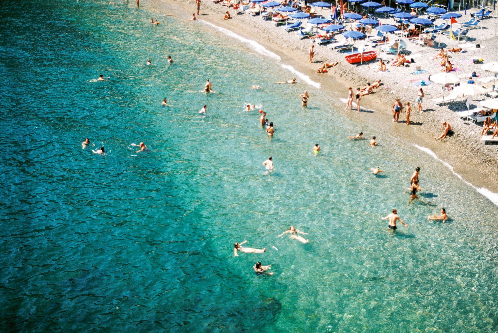 A group of people are swimming in the ocean on a beach on the Amalfi Coast.