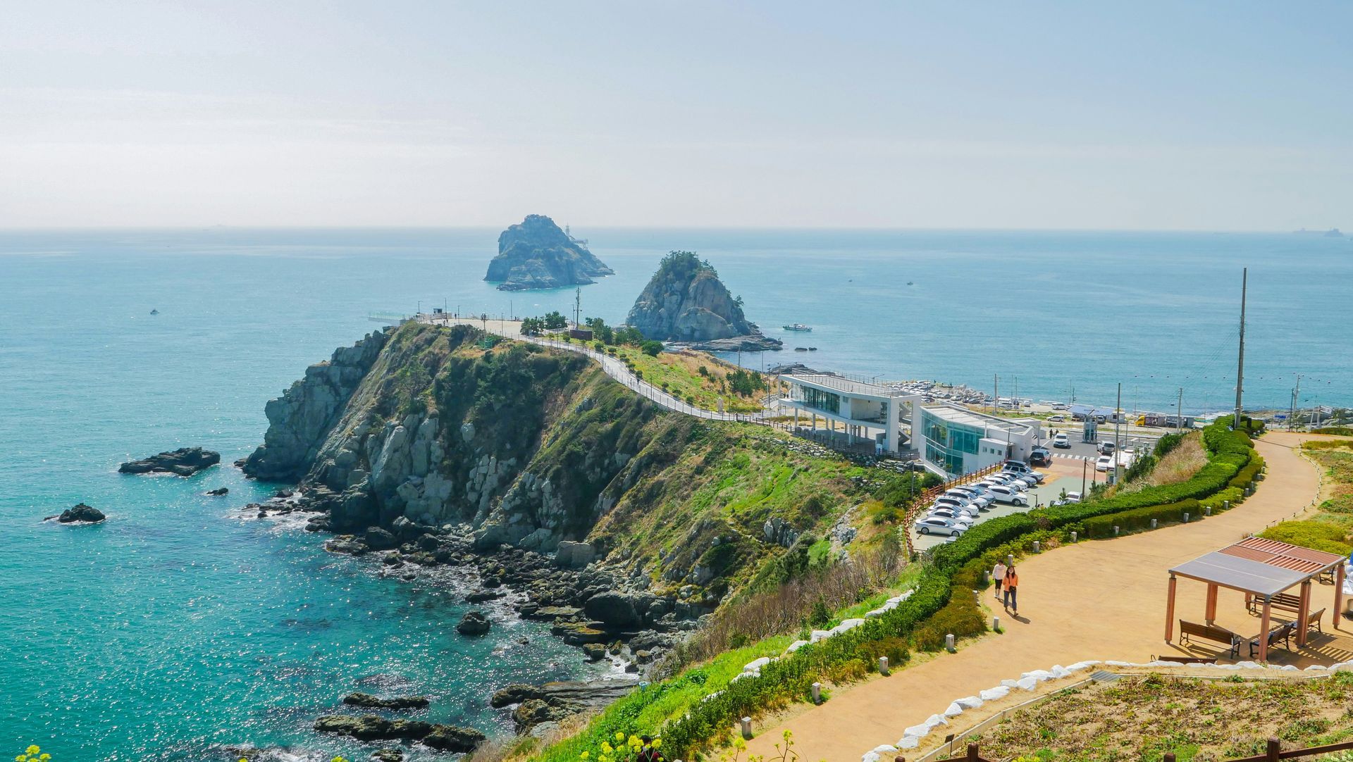 Coastal landscape with a rocky peninsula, blue sea, and two small islands in Busan, South Korea.