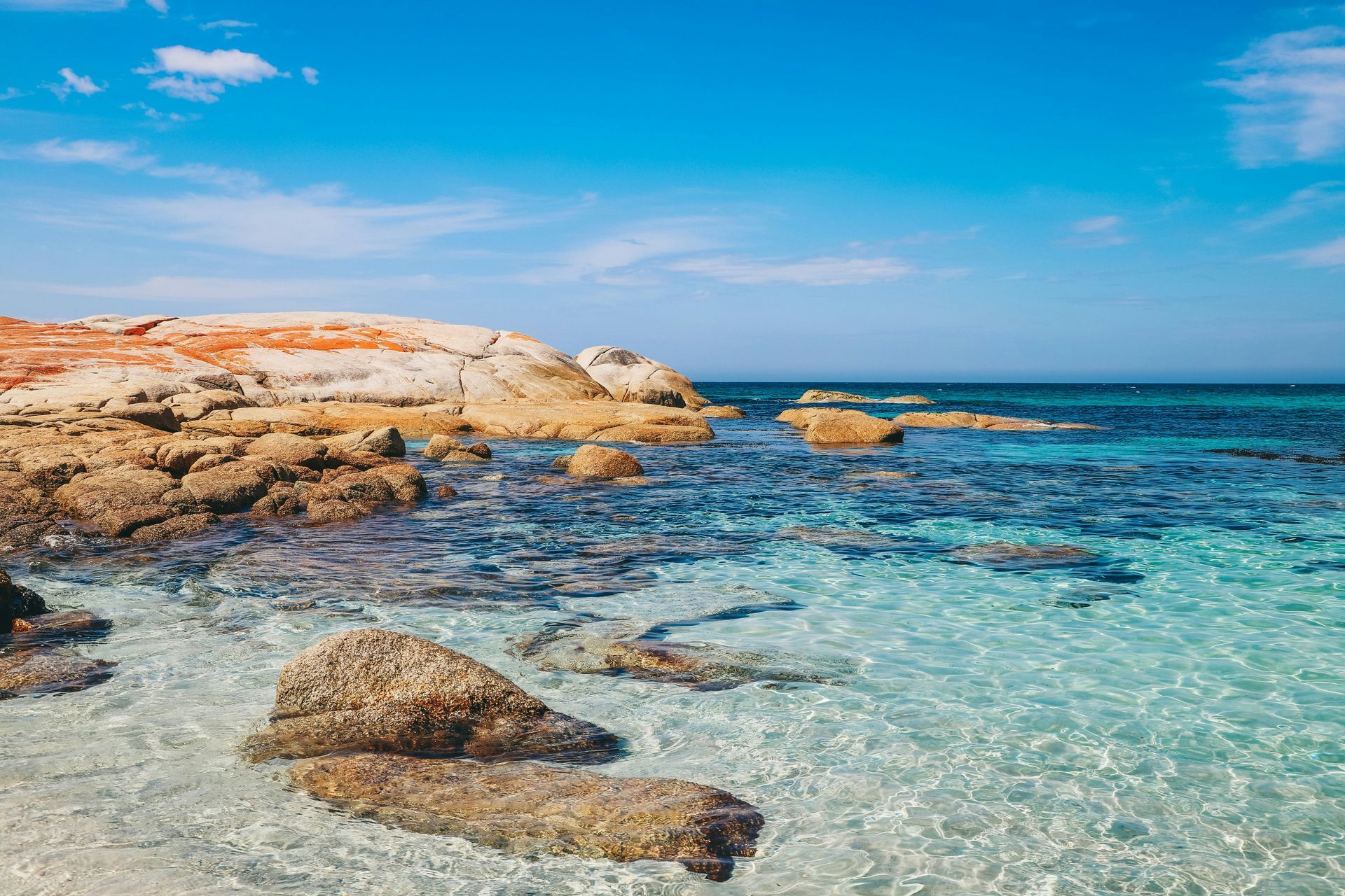 There are rocks in the water near the shore of the ocean in Tasmania, Australia.