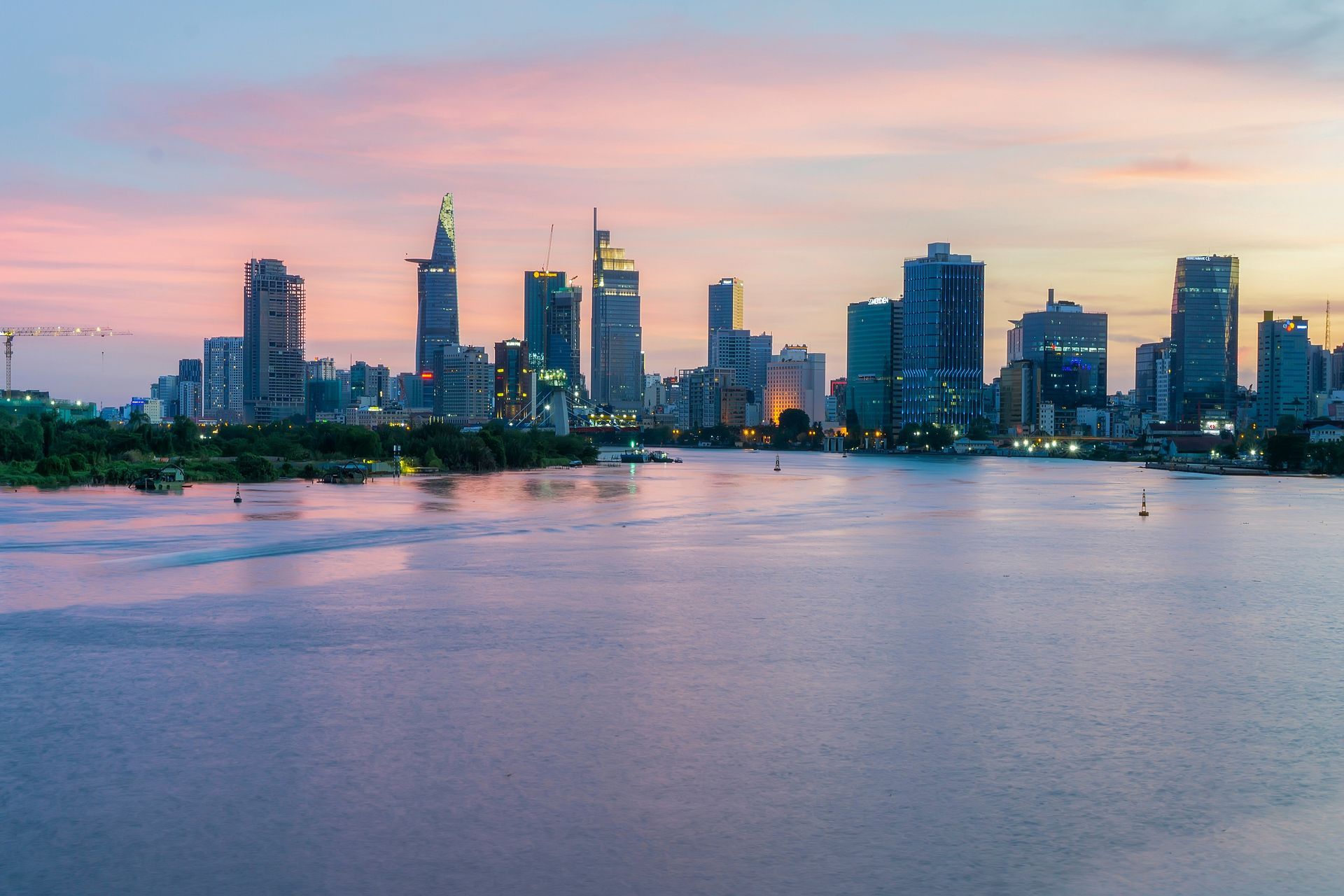 Skyline of Ho Chi Minh City at dusk, buildings silhouetted against pink and blue sky.