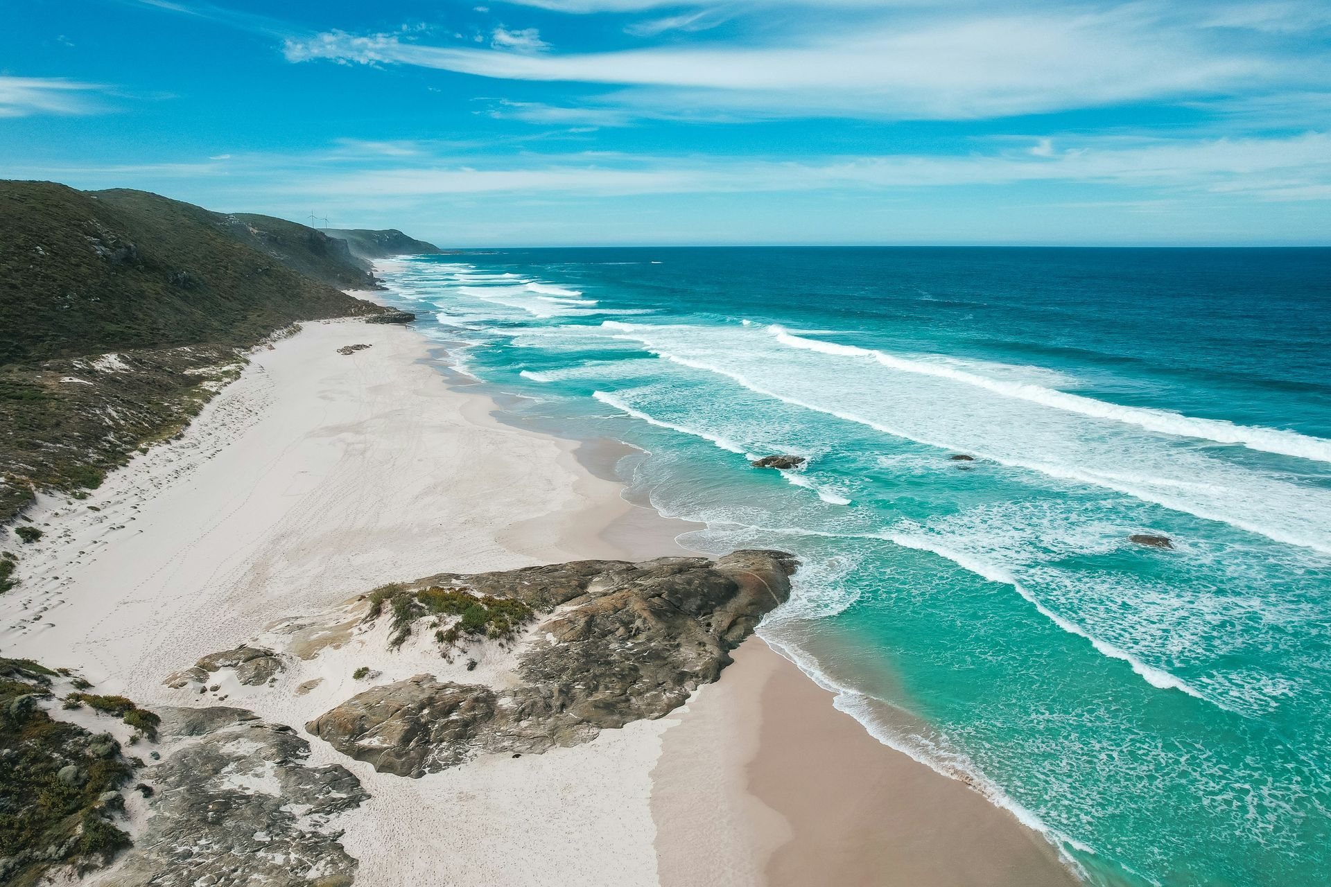 An aerial view of a beach with waves crashing on the shore in Western Australia.