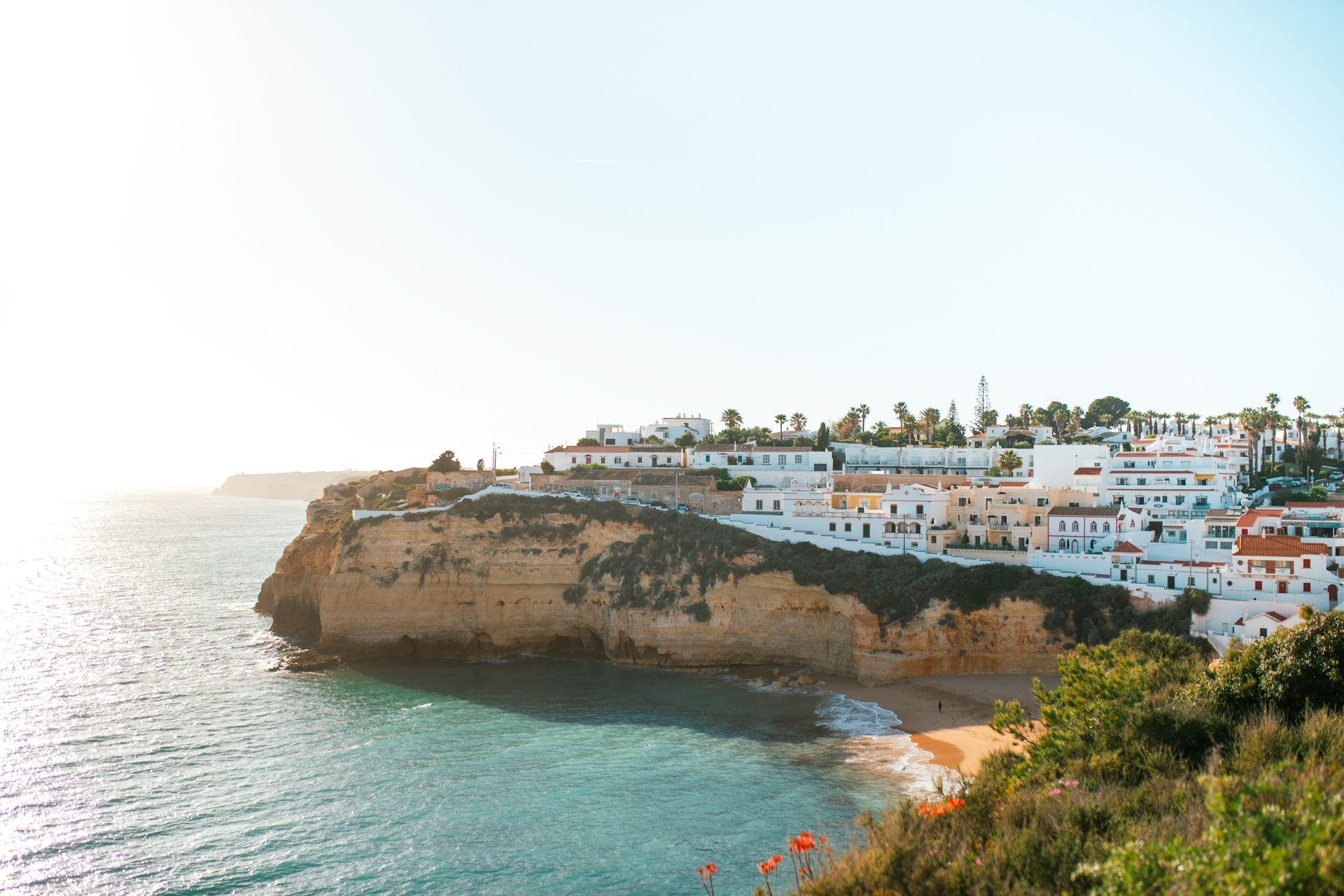 The town of Carvoeiro with white buildings on a cliff overlooking turquoise water in the Algarve, Portugal.