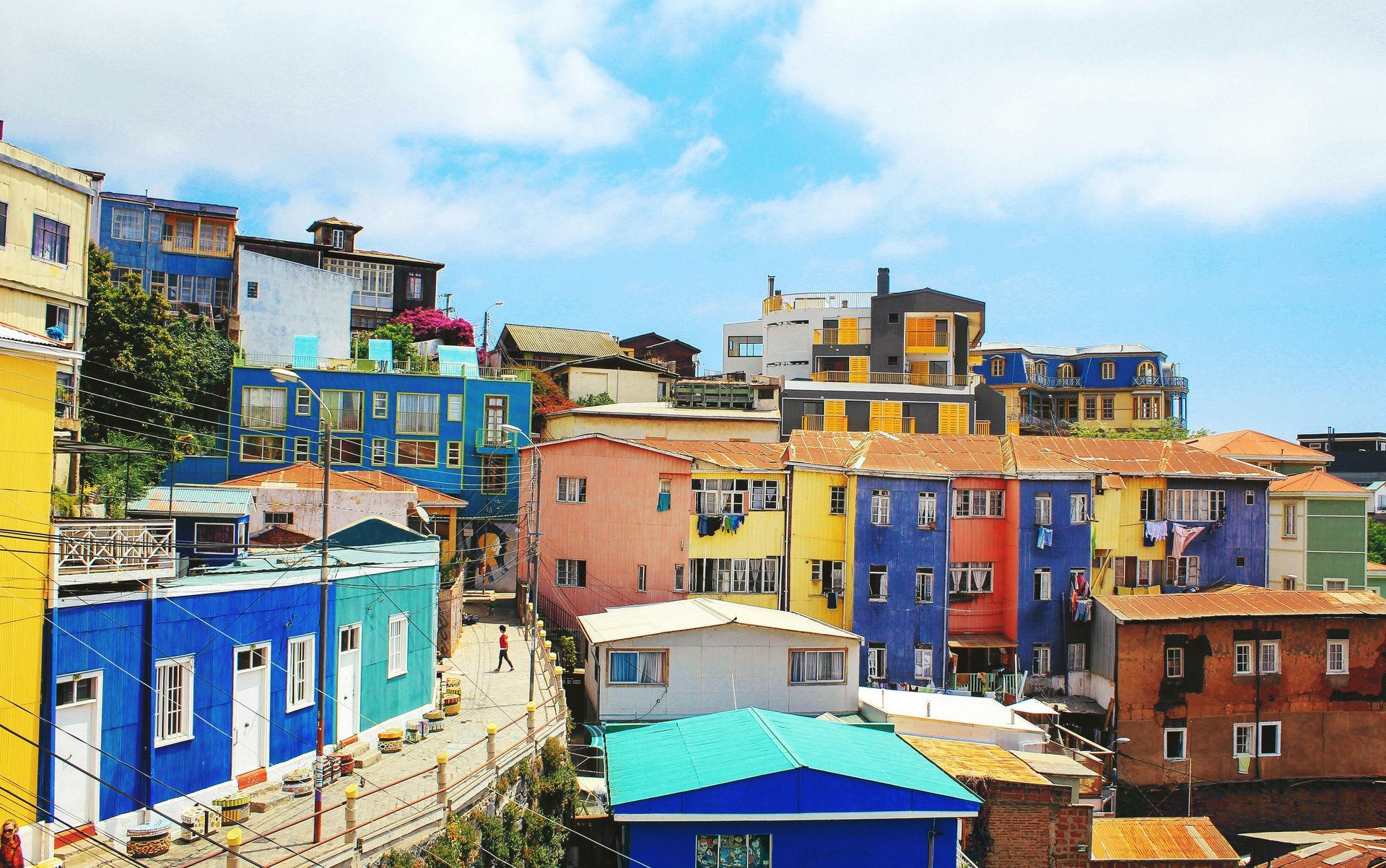 Colorful hillside buildings in Valparaíso, Chile, under a blue sky with clouds.