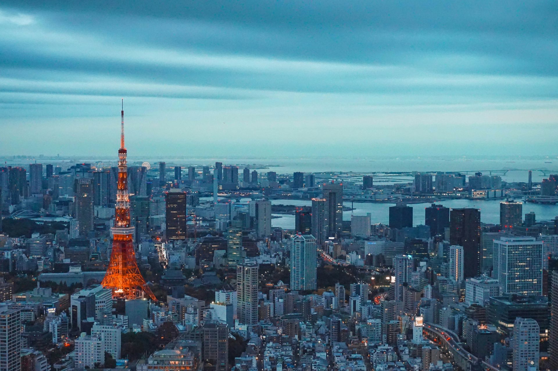 Tokyo Tower illuminated at dusk, towering over cityscape.