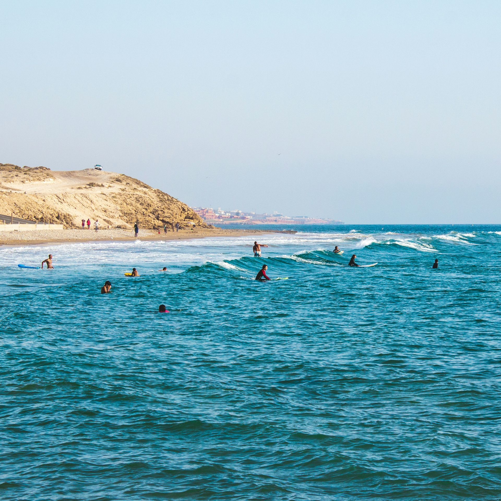 A group of people are swimming in the ocean near a beach in Taghazout, Morocco.