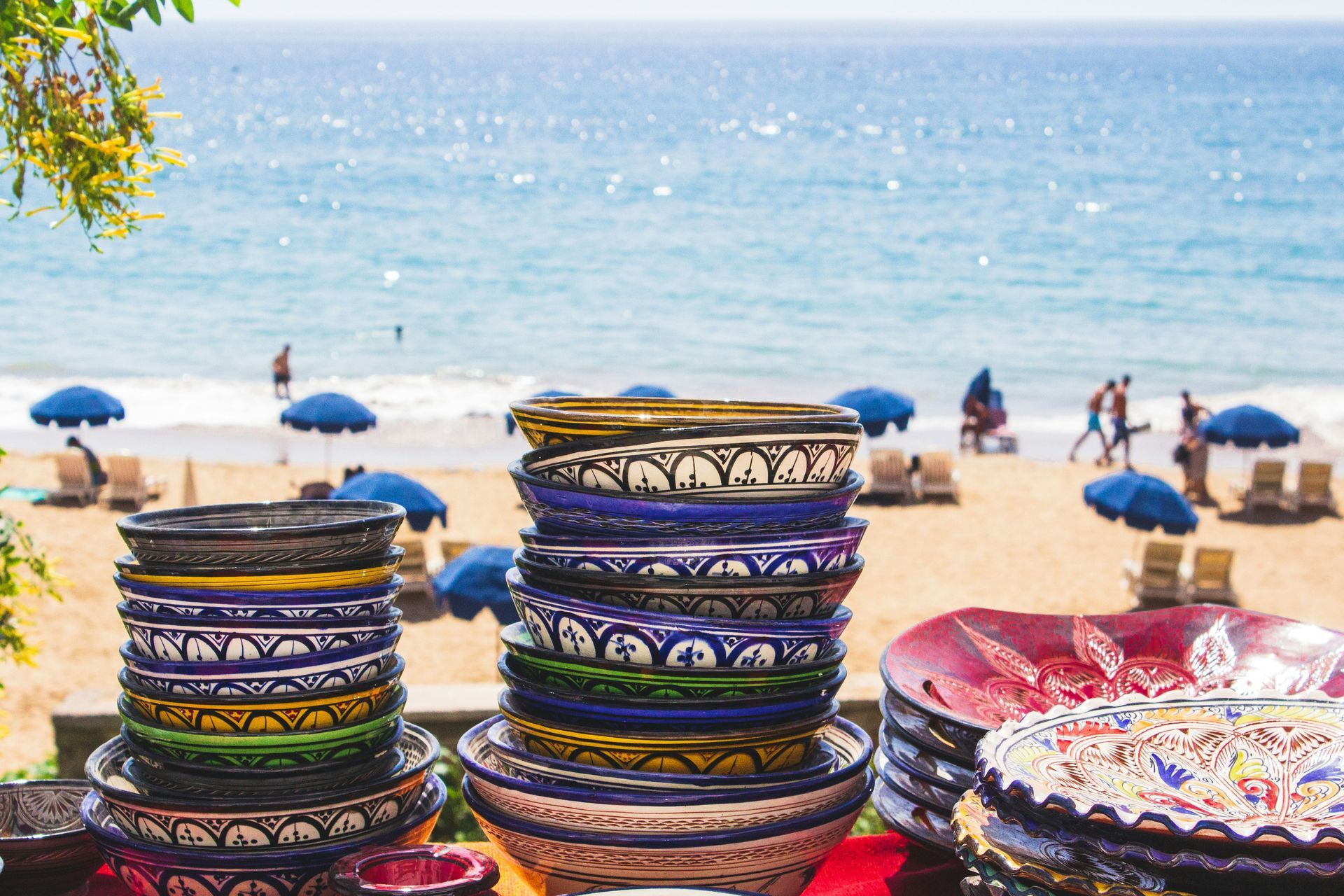 A stack of bowls and plates on a table on a beach in Taghazout, Morocco.