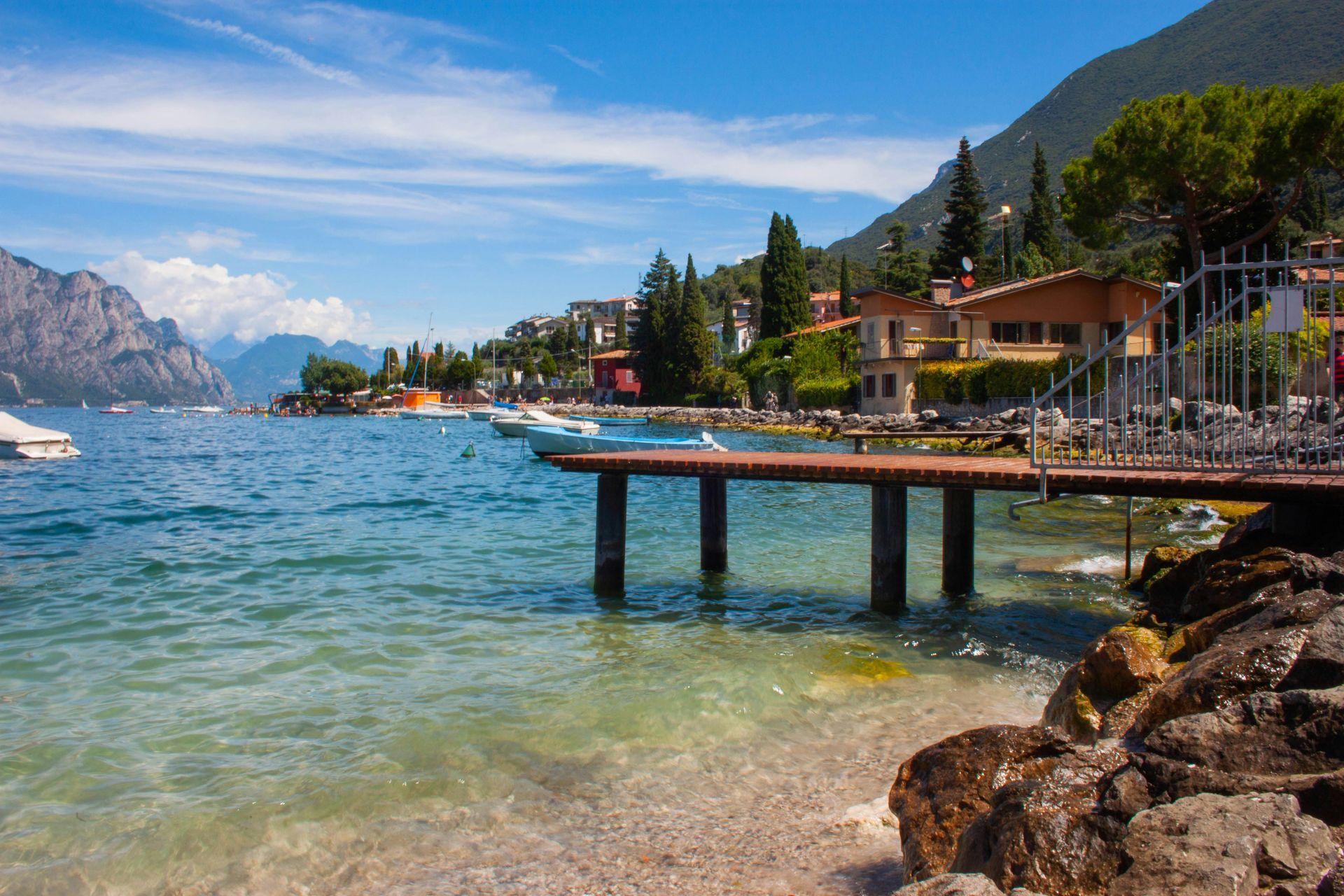 A dock leading to Lake Garda with mountains in the background in Italy.