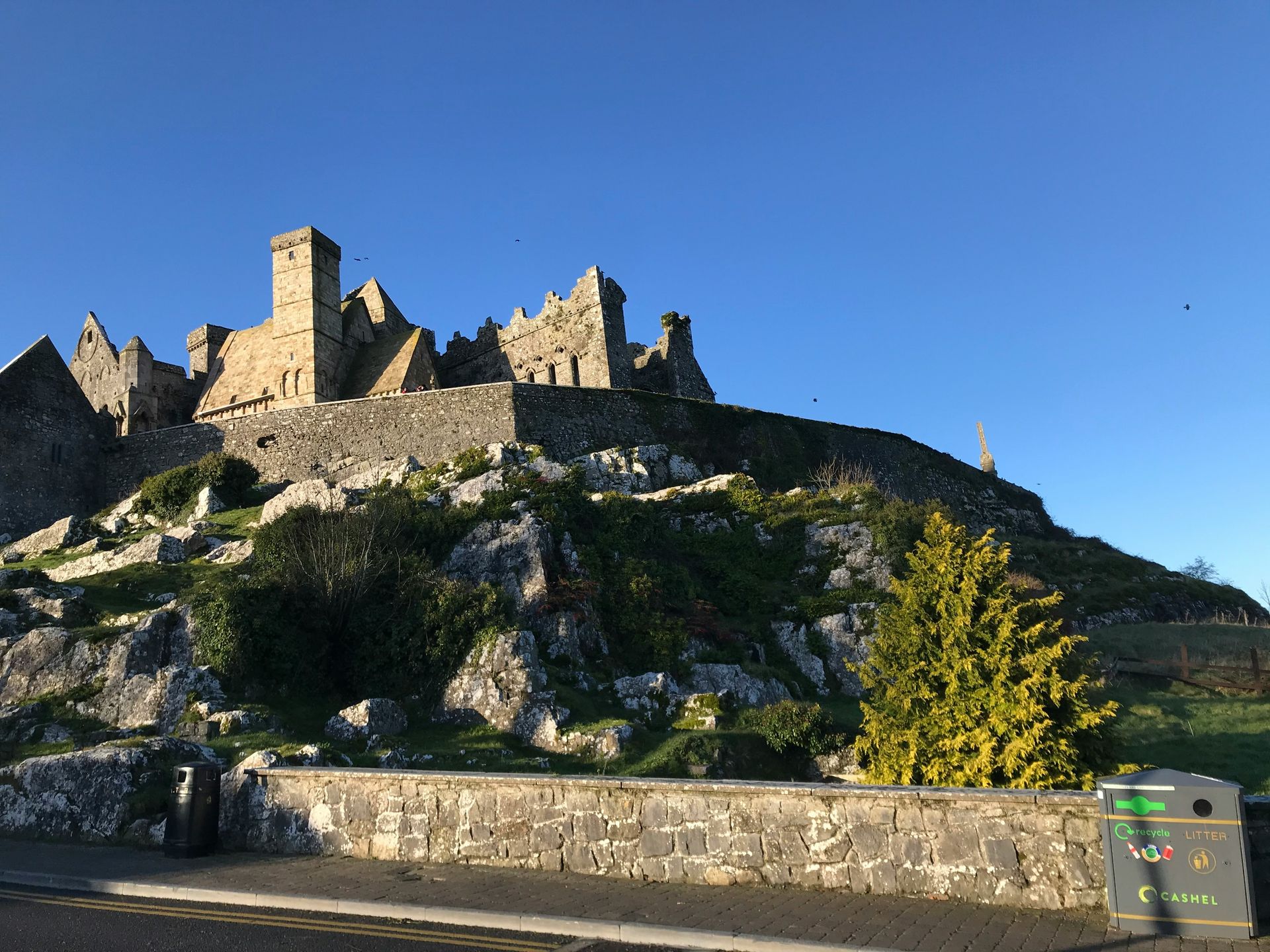 Ruined stone castle atop a rocky hill under a clear blue sky at the Rock of Cashel, Ireland.