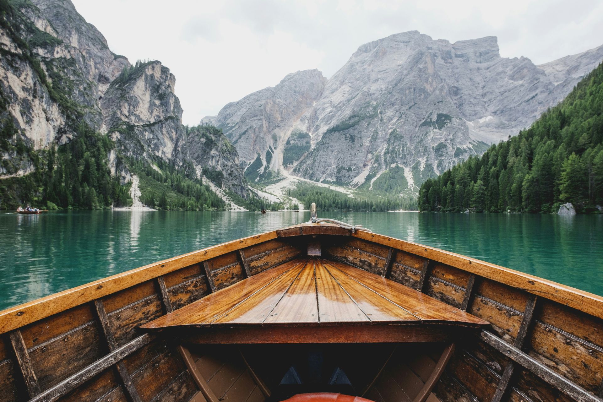 A wooden boat is floating on a lake with the Dolomites in the background in Italy.