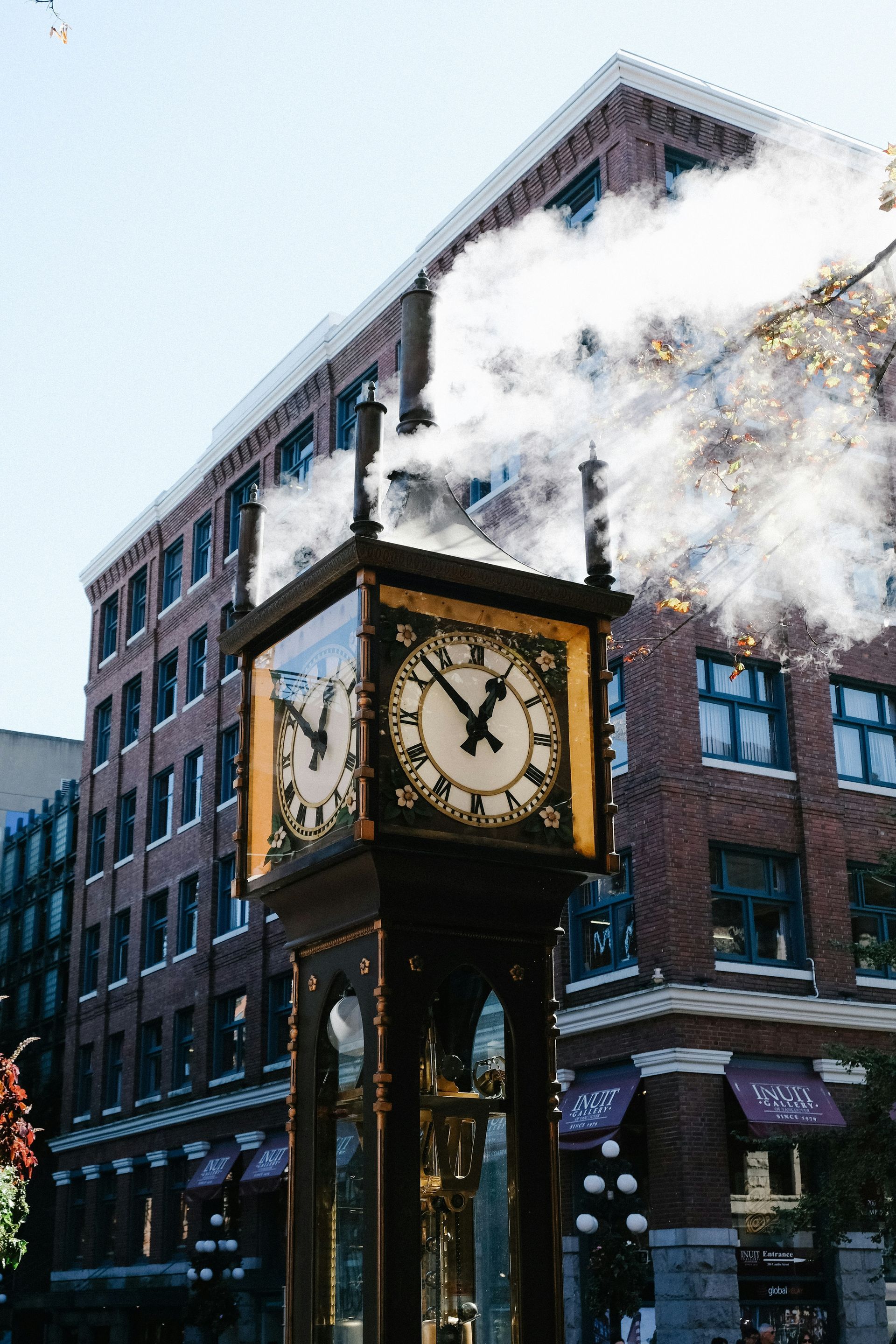 Steam clock in Gastown, Vancouver, against a brick building. The clock's face shows 2:56. White steam rises from the clock.