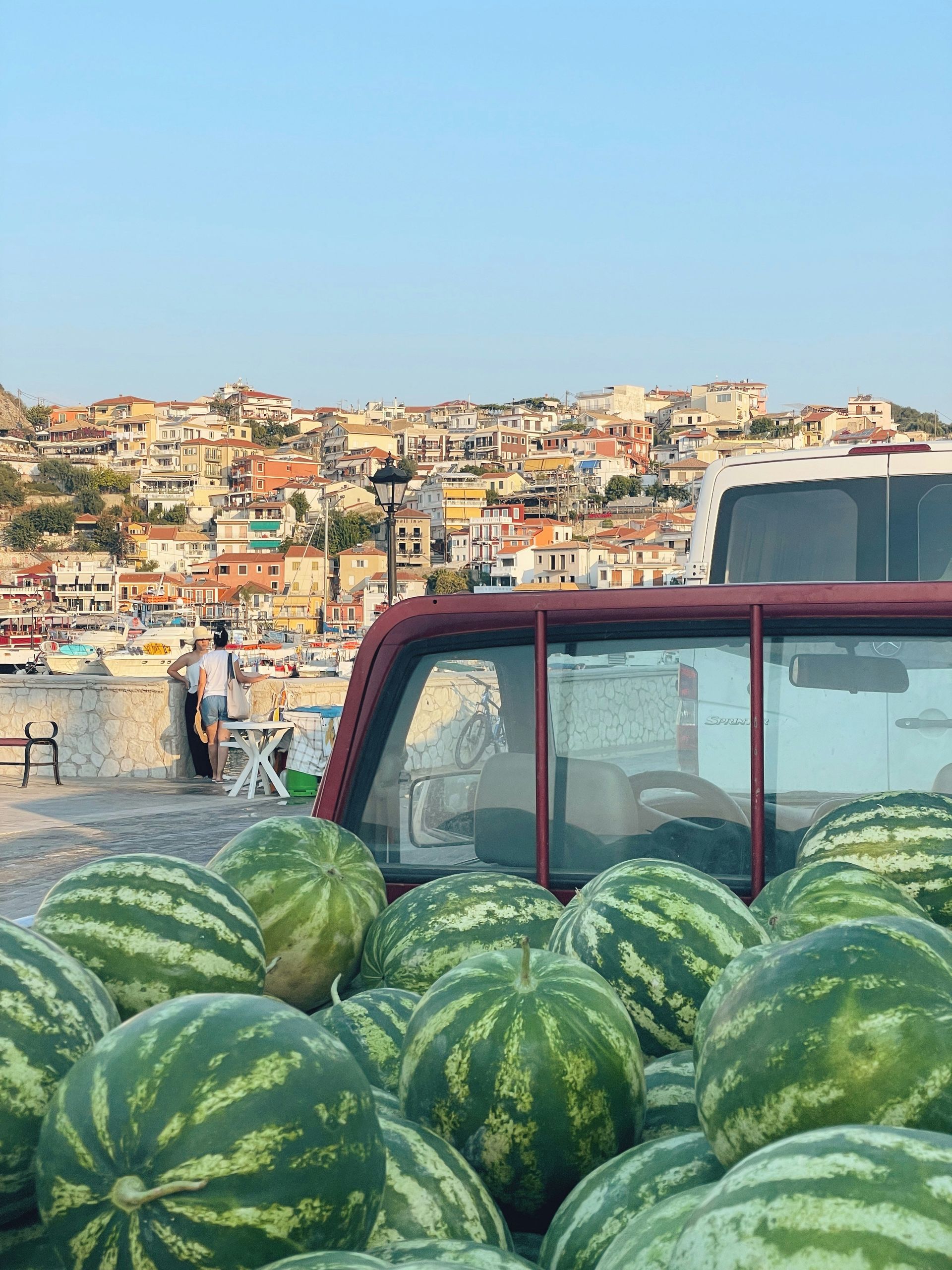 A truck filled with watermelons is parked in front of Parga, Greece.