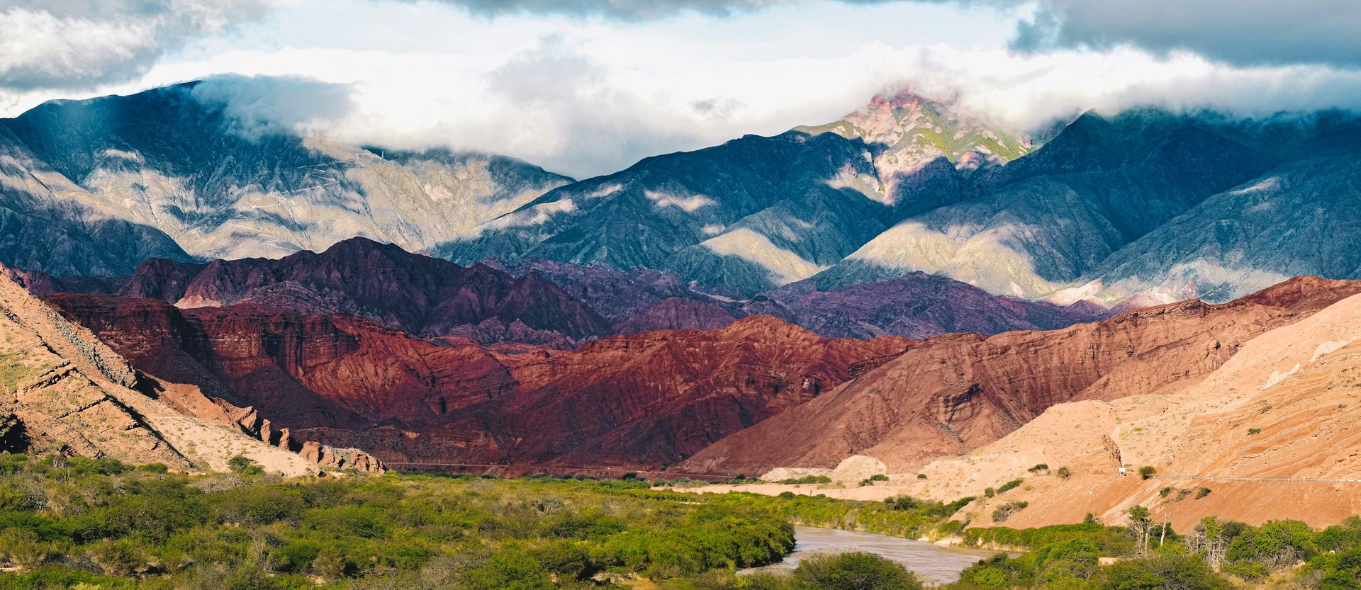 Rainbow mountains with a valley and green vegetation in the foreground in the Cerro Hornoca in Salta, Argentina.