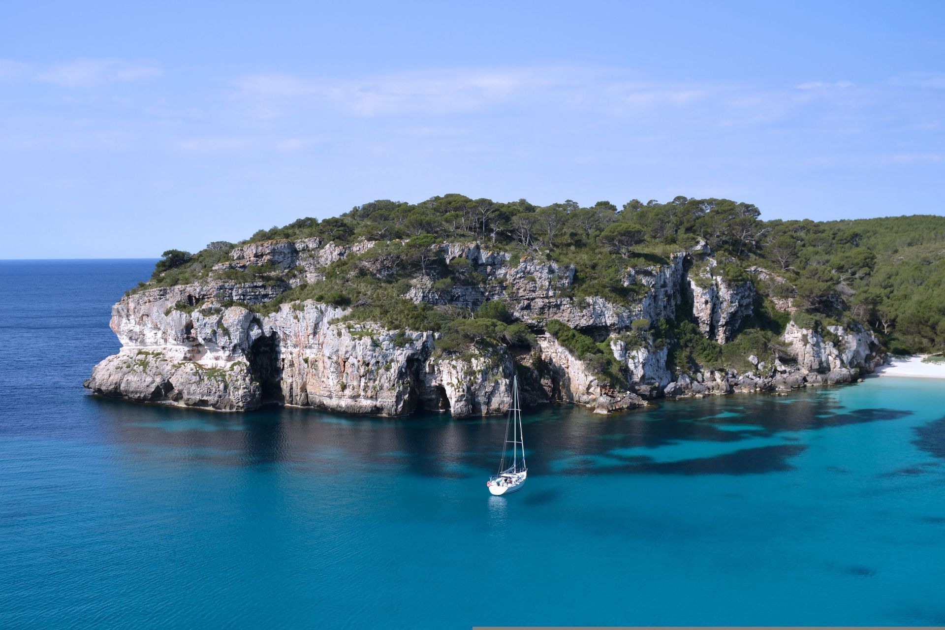 A sailboat is docked on the island of Mallorca in the middle of the ocean.