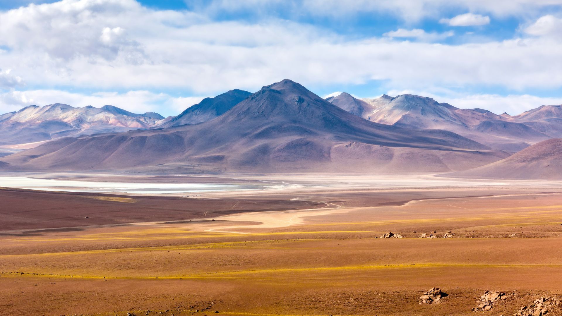 Desert landscape with mountains under a blue, partly cloudy sky in the Atacama Desert, Chile.