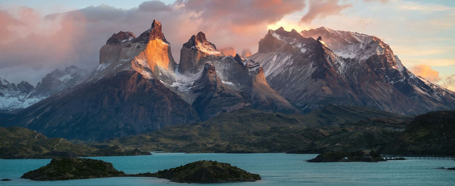 Mountains with snowy peaks and sunset sky reflect in the blue lake in Patagonia.