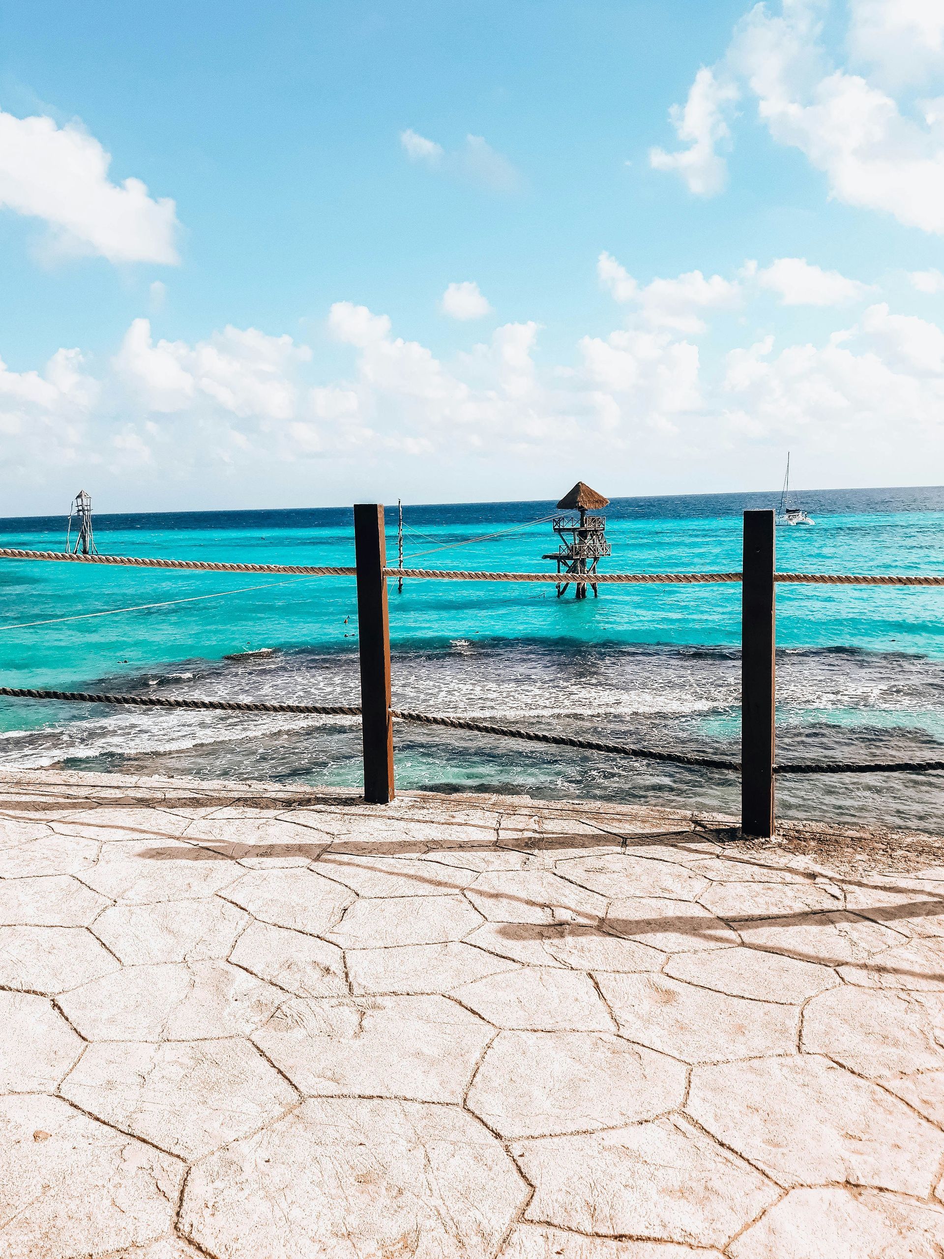 A wooden fence surrounds a beach with the ocean in the background on Isla Mujeres.