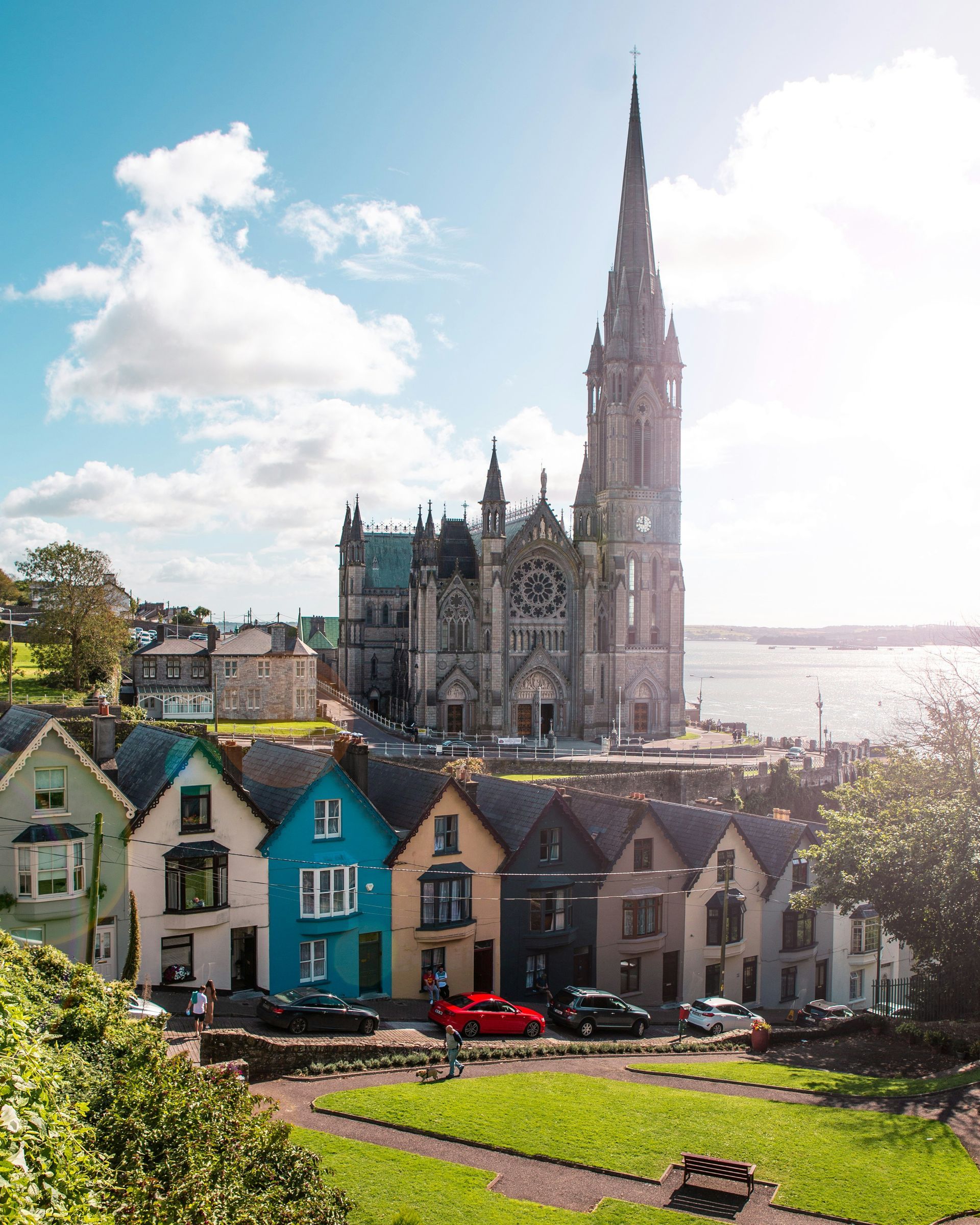 Colorful houses line a hill with a cathedral tower overlooking the water in Cork, Ireland.