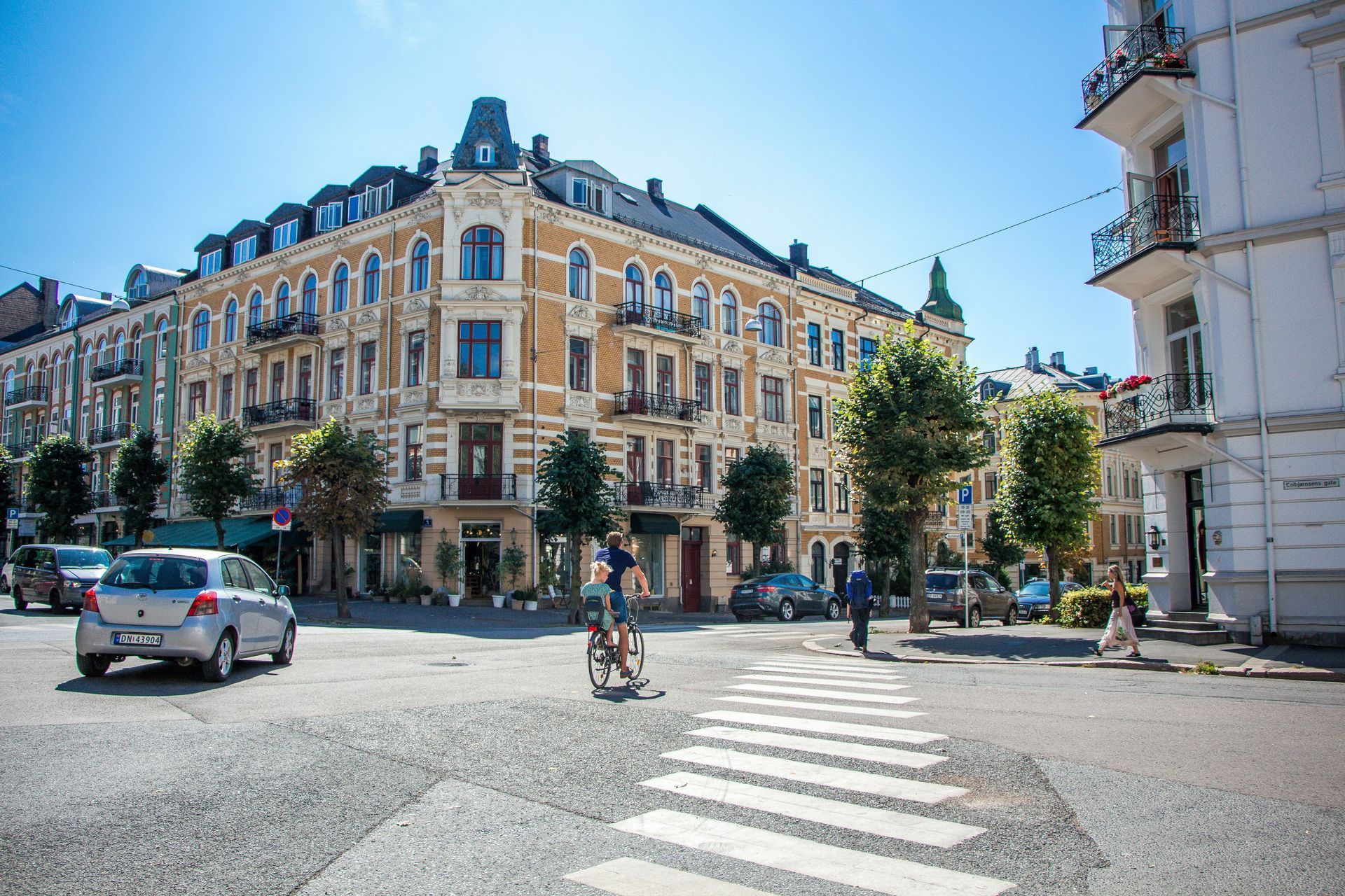 Street scene with crosswalk, buildings, cars, and people in Oslo, Norway.