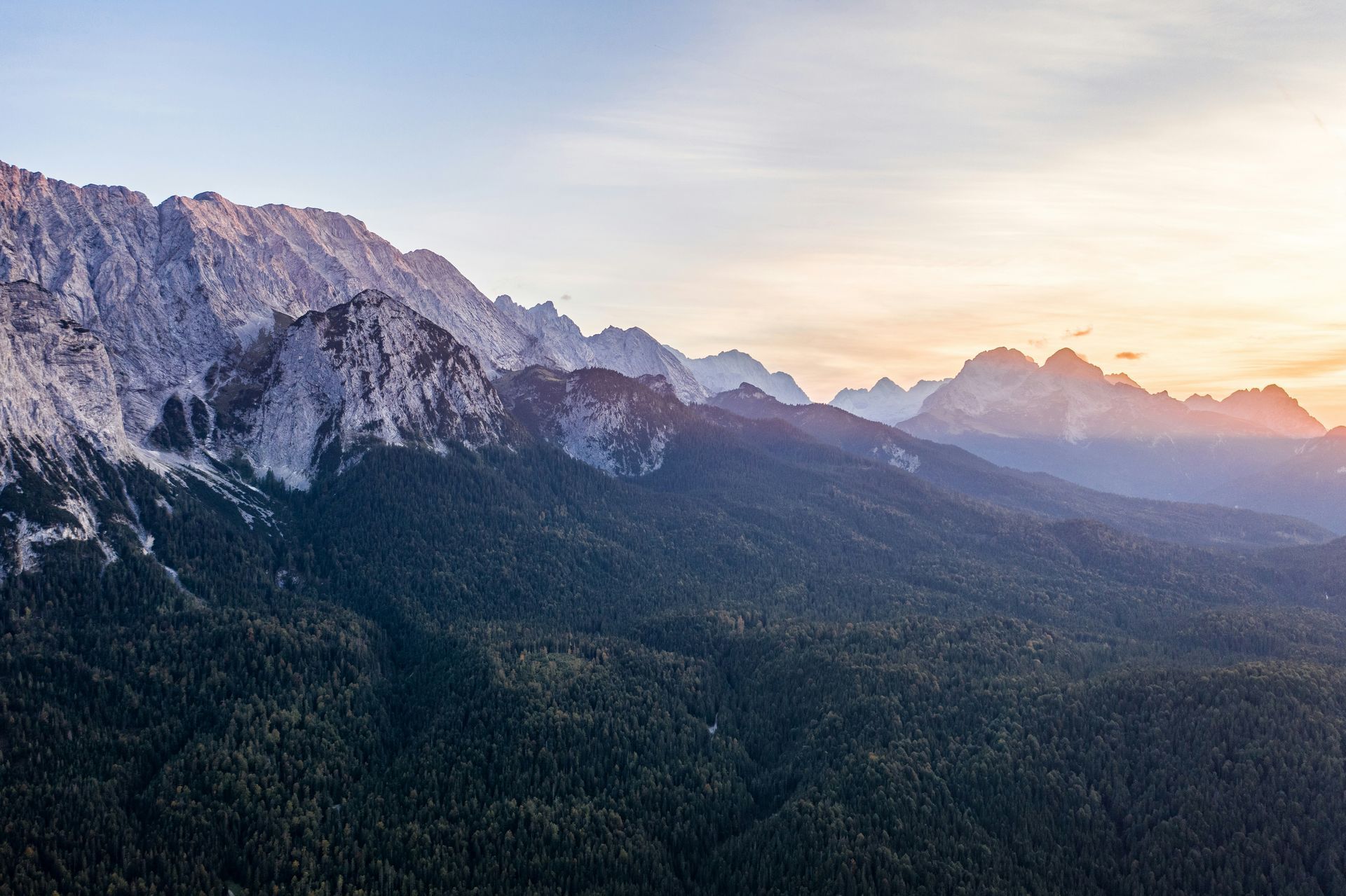 Mountains at sunset with a forest in the foreground and a colorful sky in Mittenwald, Germany.
