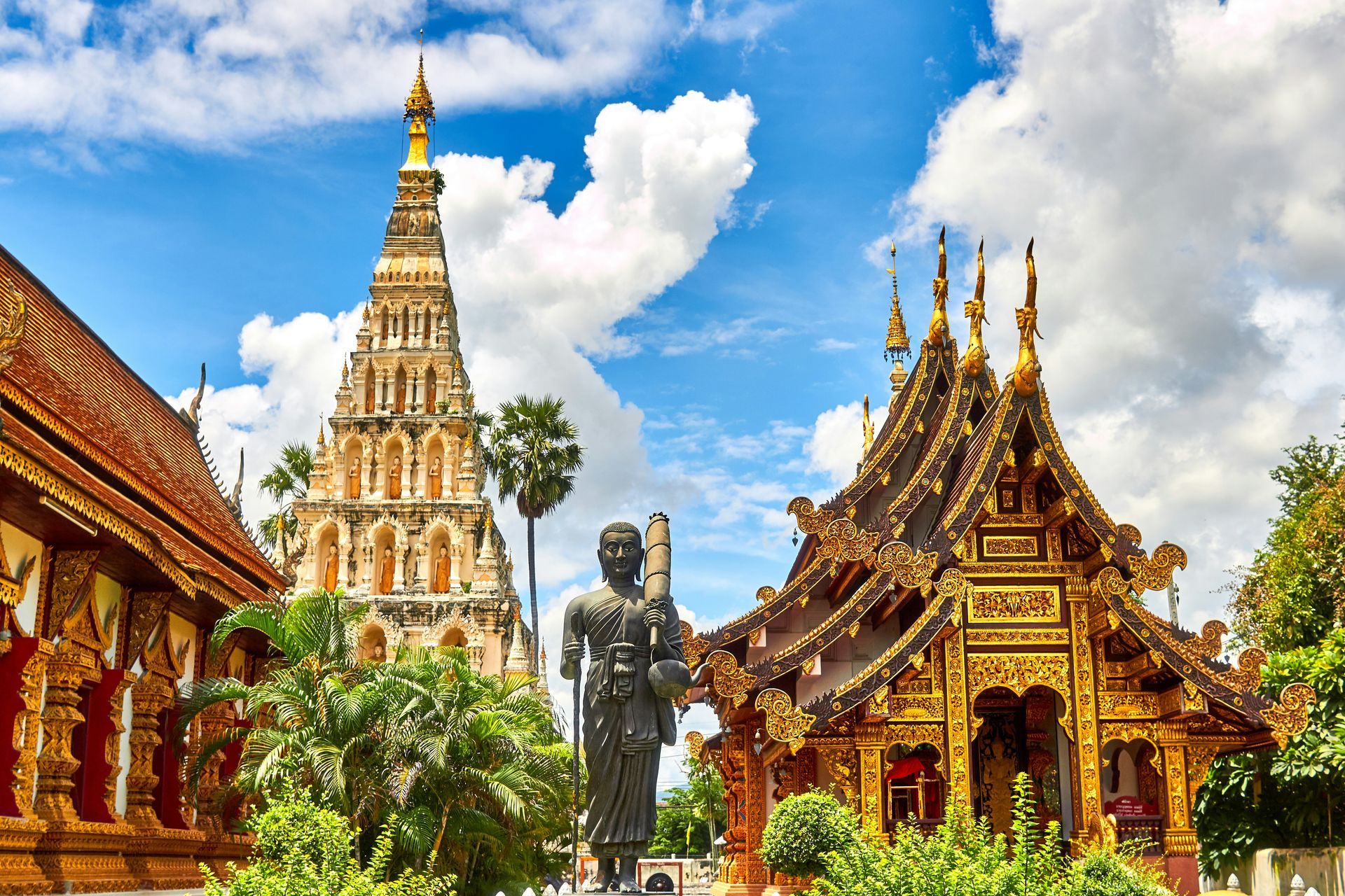 A statue of a man is standing in front of a temple in Thailand.