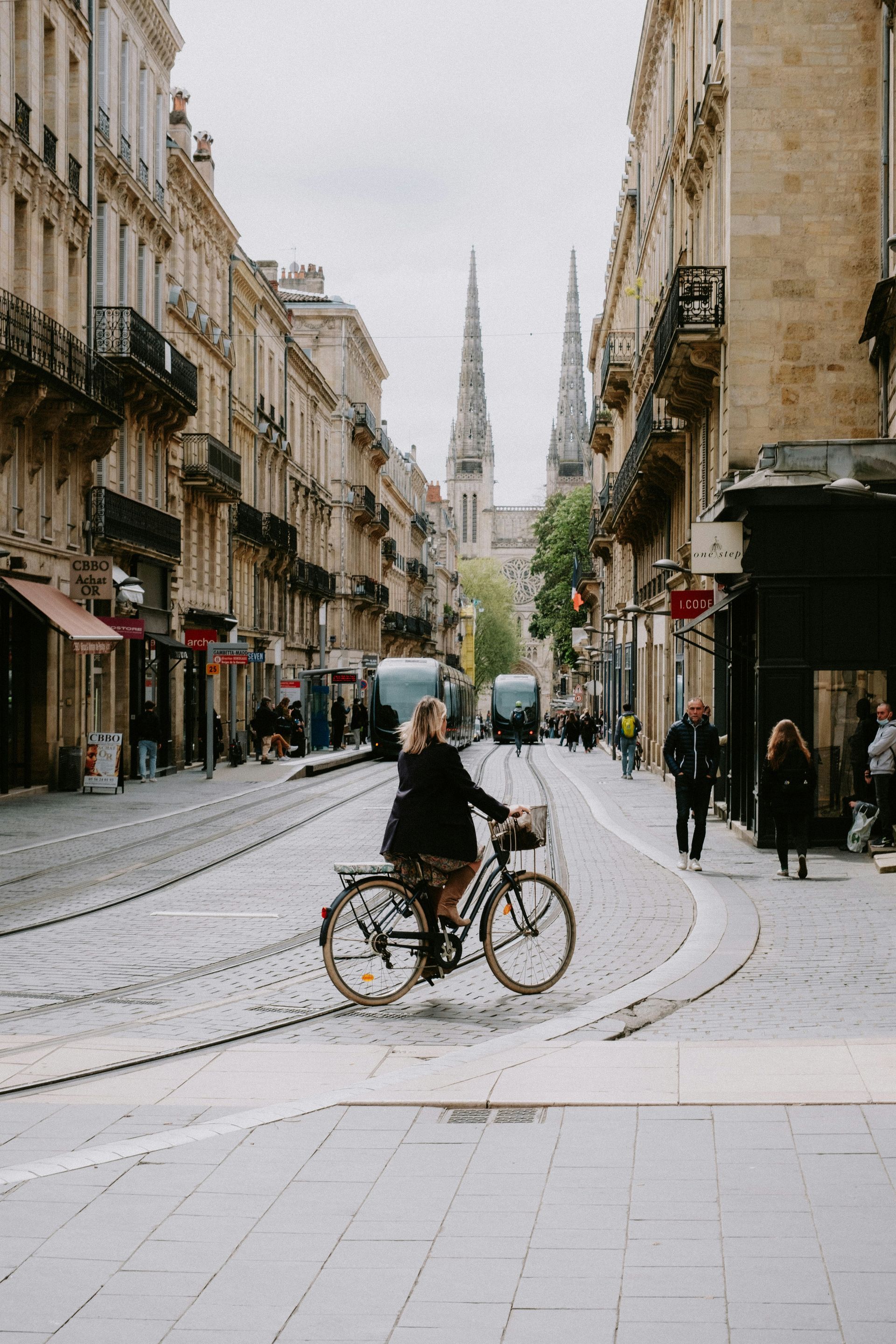 A woman is riding a bike down a city street in Bordeaux, France.