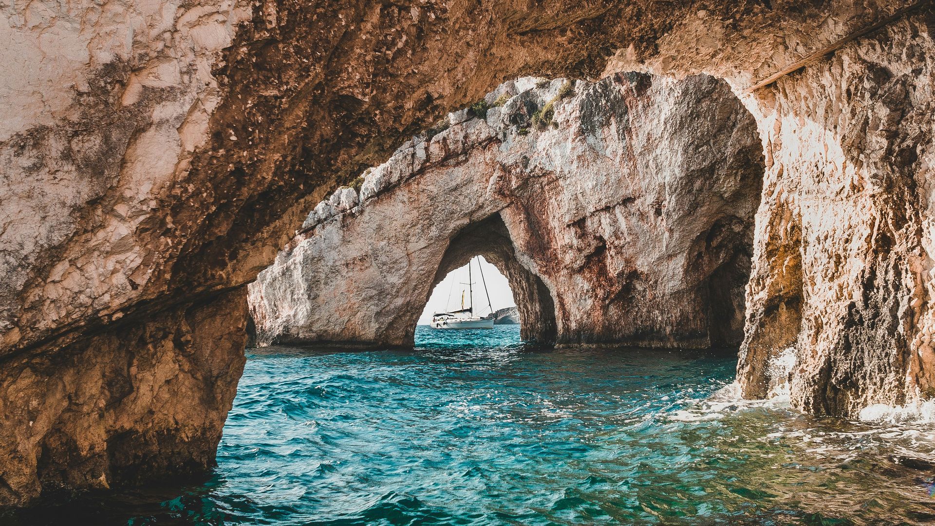 A boat is going through a cave in the ocean in Zakynthos, Greece.