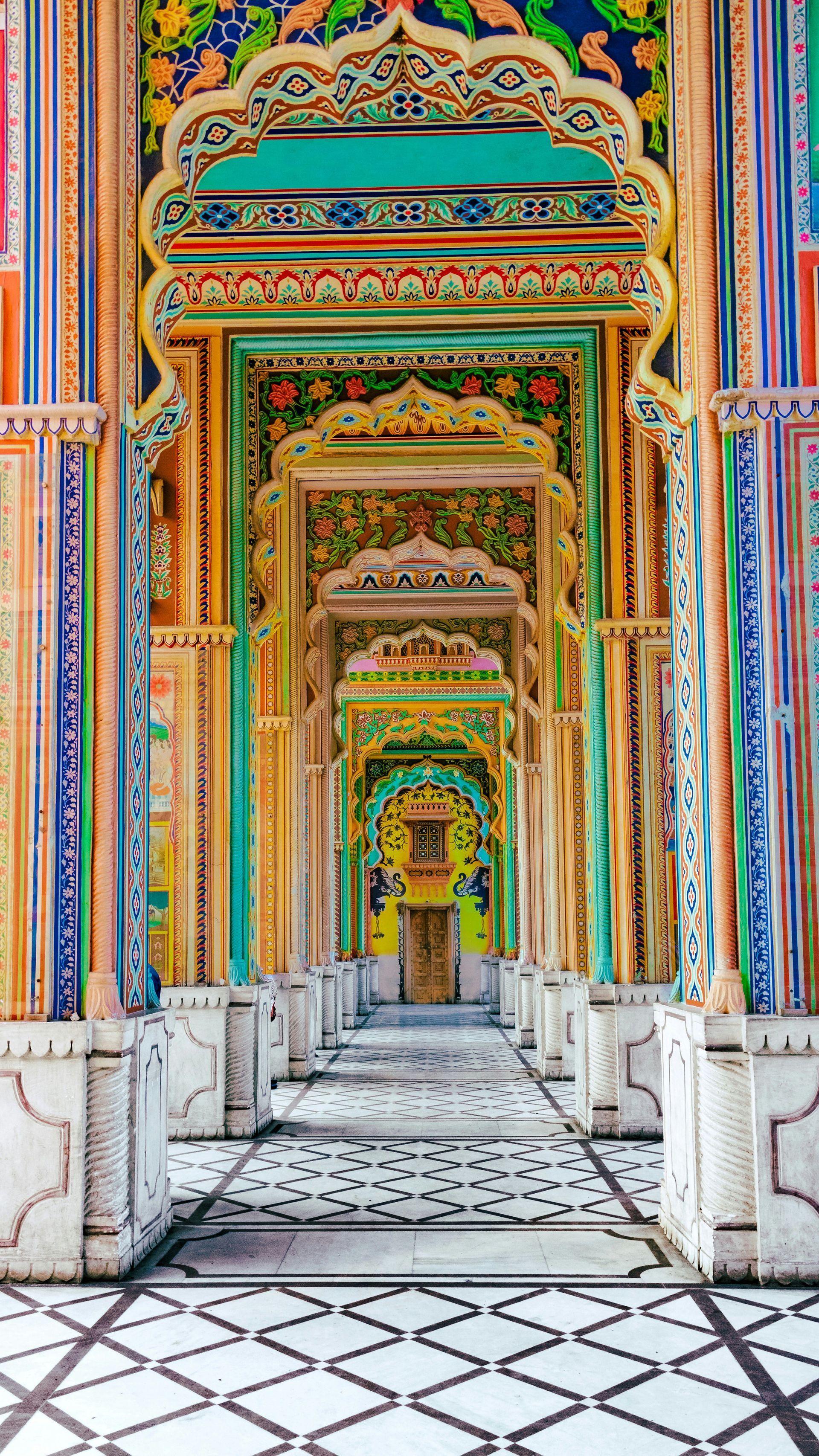 Ornate, colorful doorways and arches leading towards a distant golden door in Jaipur, India.
