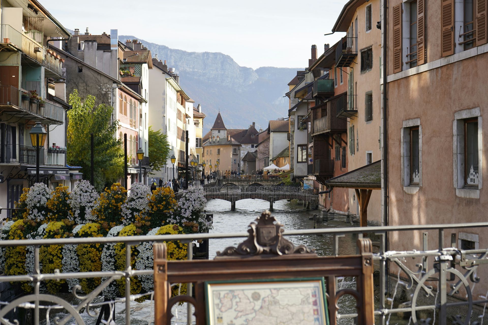 A bridge over a river in a city with mountains in the background in Annecy, France.