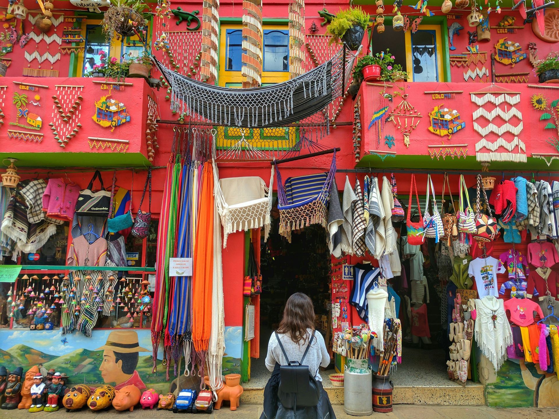 A woman is walking in front of a colorful store in Cartagena, Colombia.