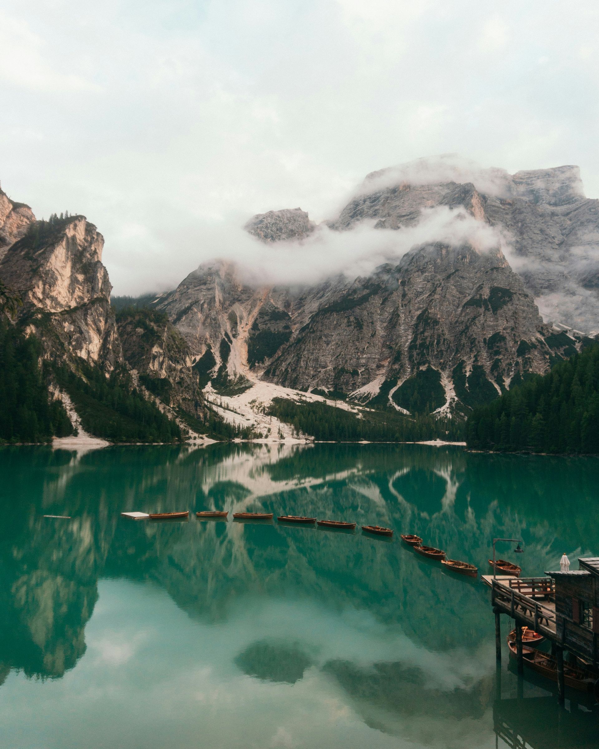 Lake Braies surrounded by the Dolomites and trees with boats in the water in Italy.