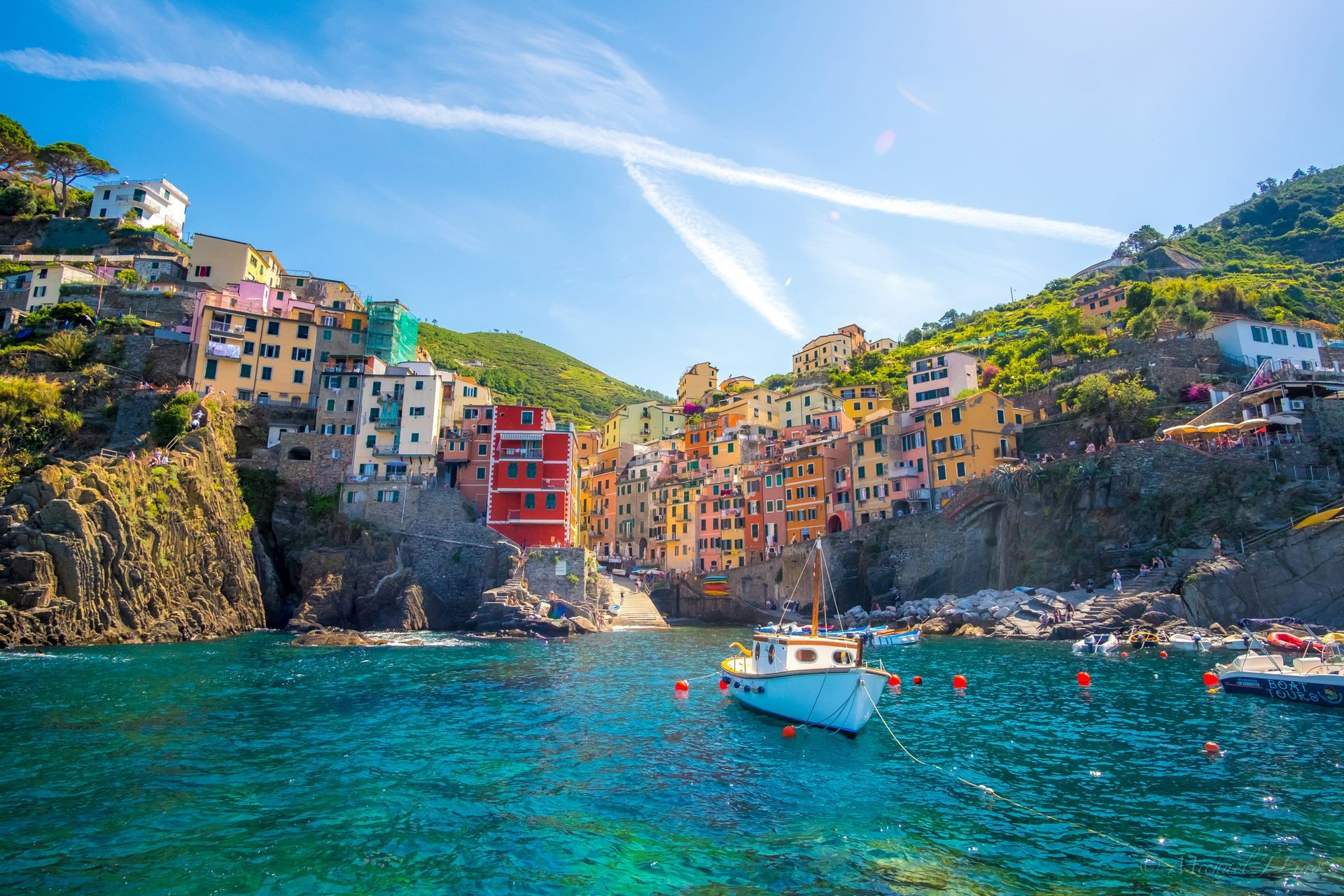 A boat is docked in the water near a small town in Cinque Terre, Italy.