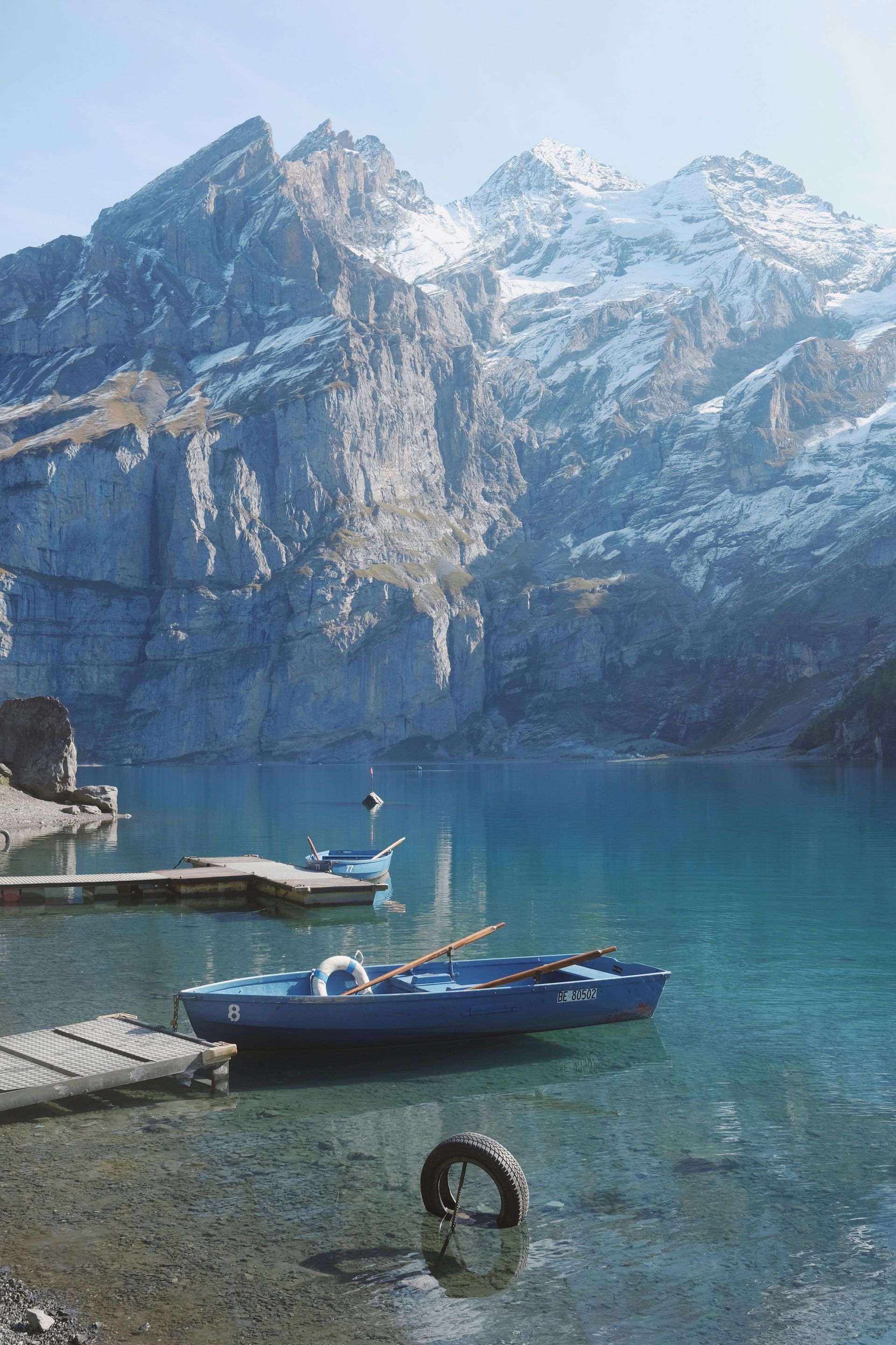 Blue boats on the clear Lake Oeschinensee, rocky mountains in the background in Kandersteg, Switzerland.