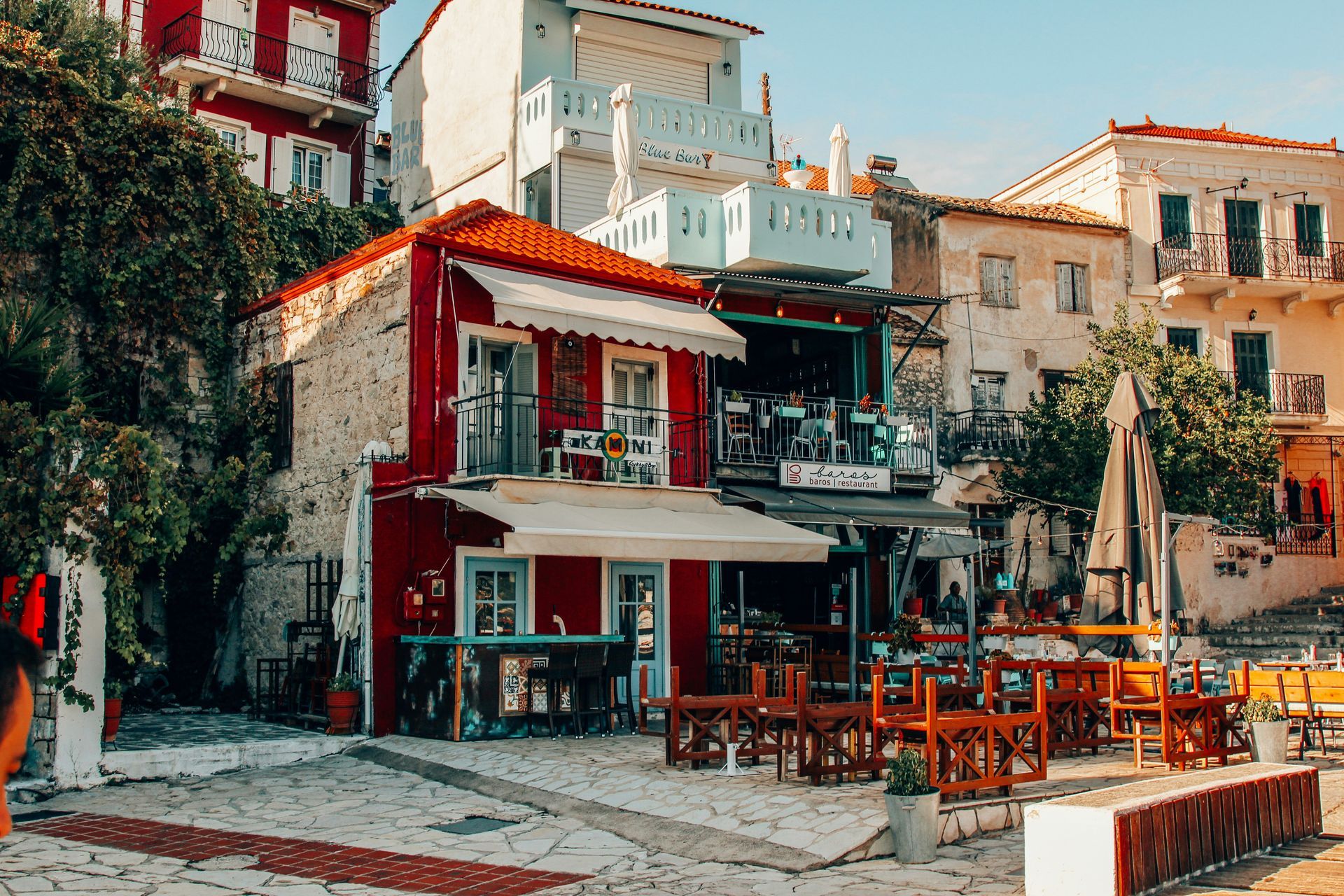 A red building with tables and chairs in front of it in Parga, Greece.