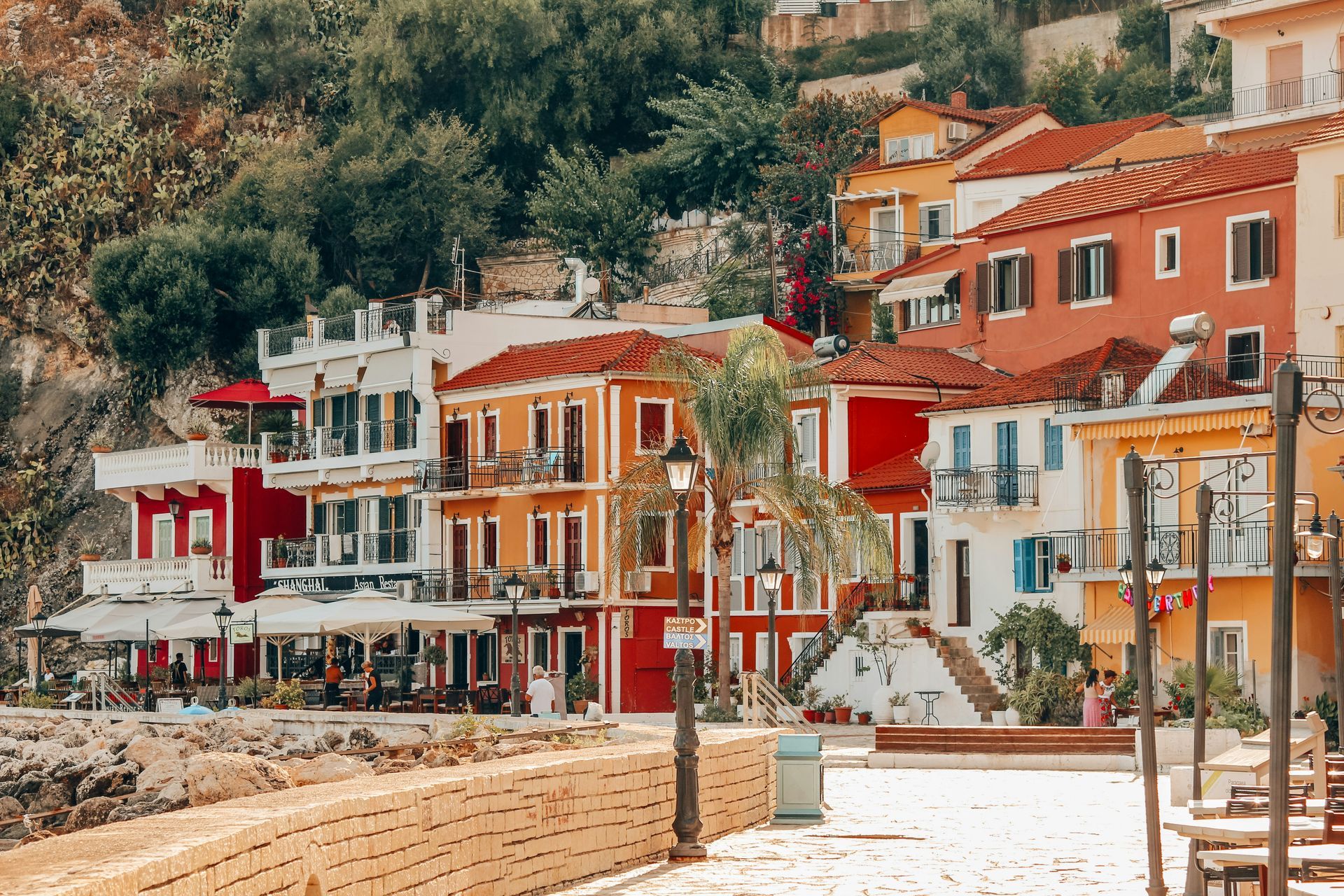 A row of colorful buildings on a hillside next to a body of water in Parga, Greece.