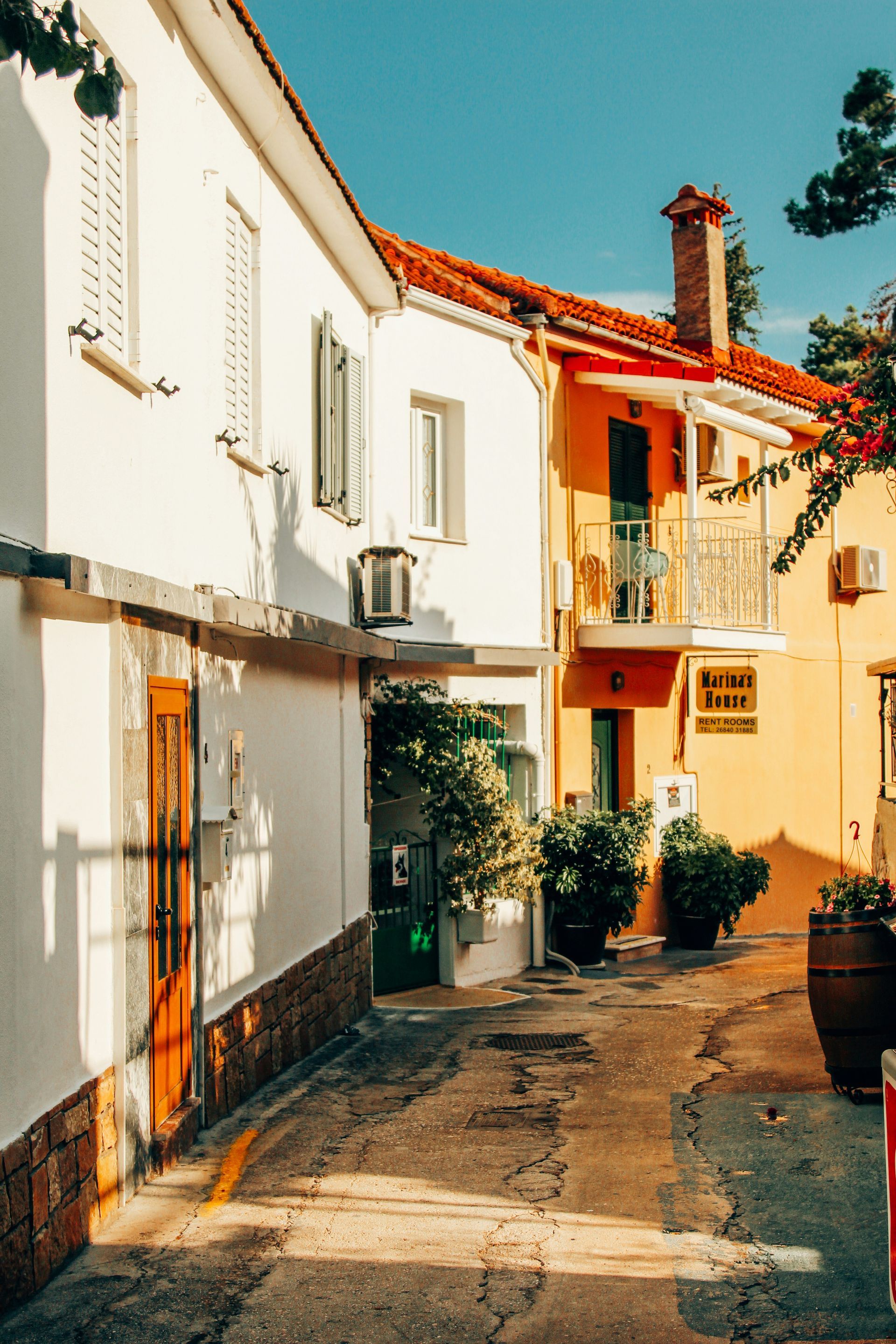 A narrow alleyway between two buildings with a red tiled roof in Parga, Greece.