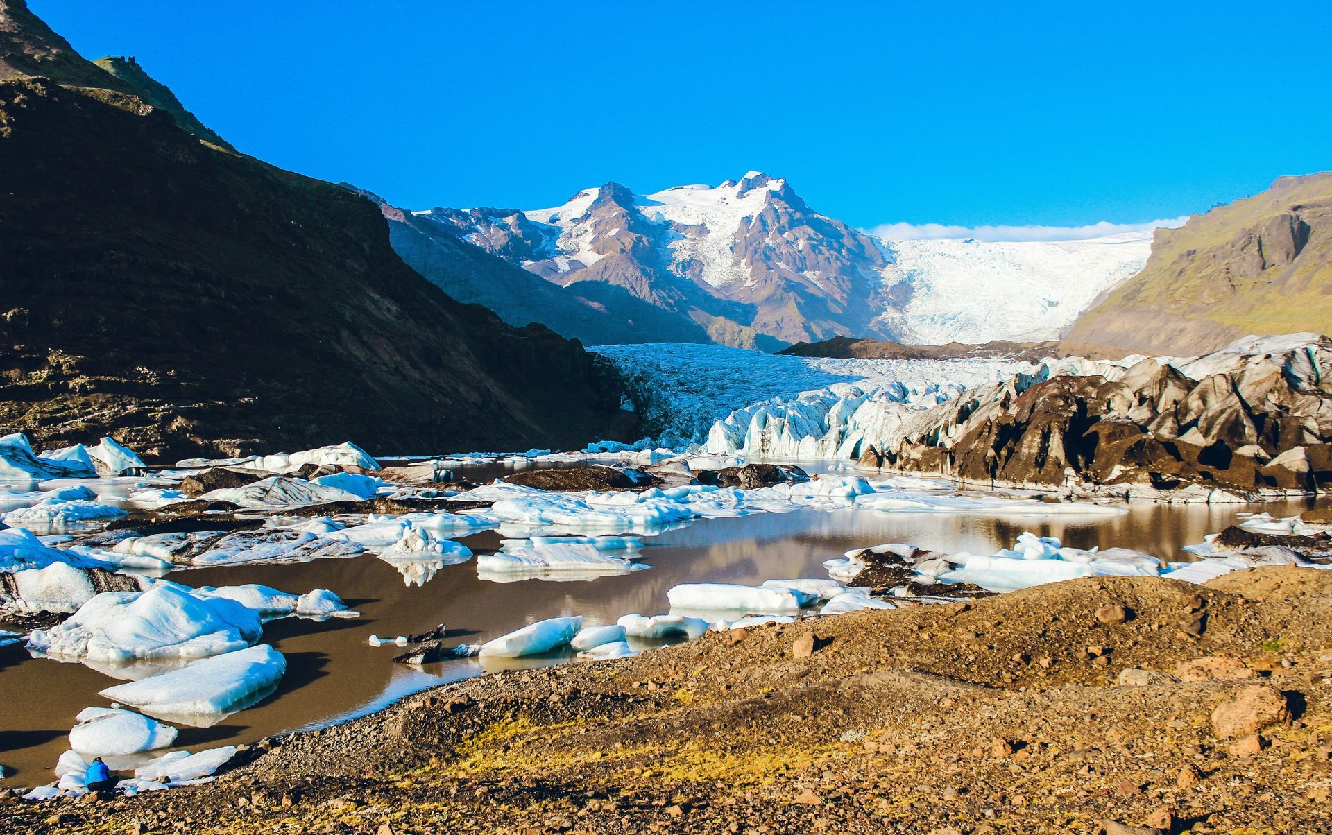 Glacier landscape with icebergs in a lake, mountains, and blue sky at Vatnajökull National Park, Iceland.