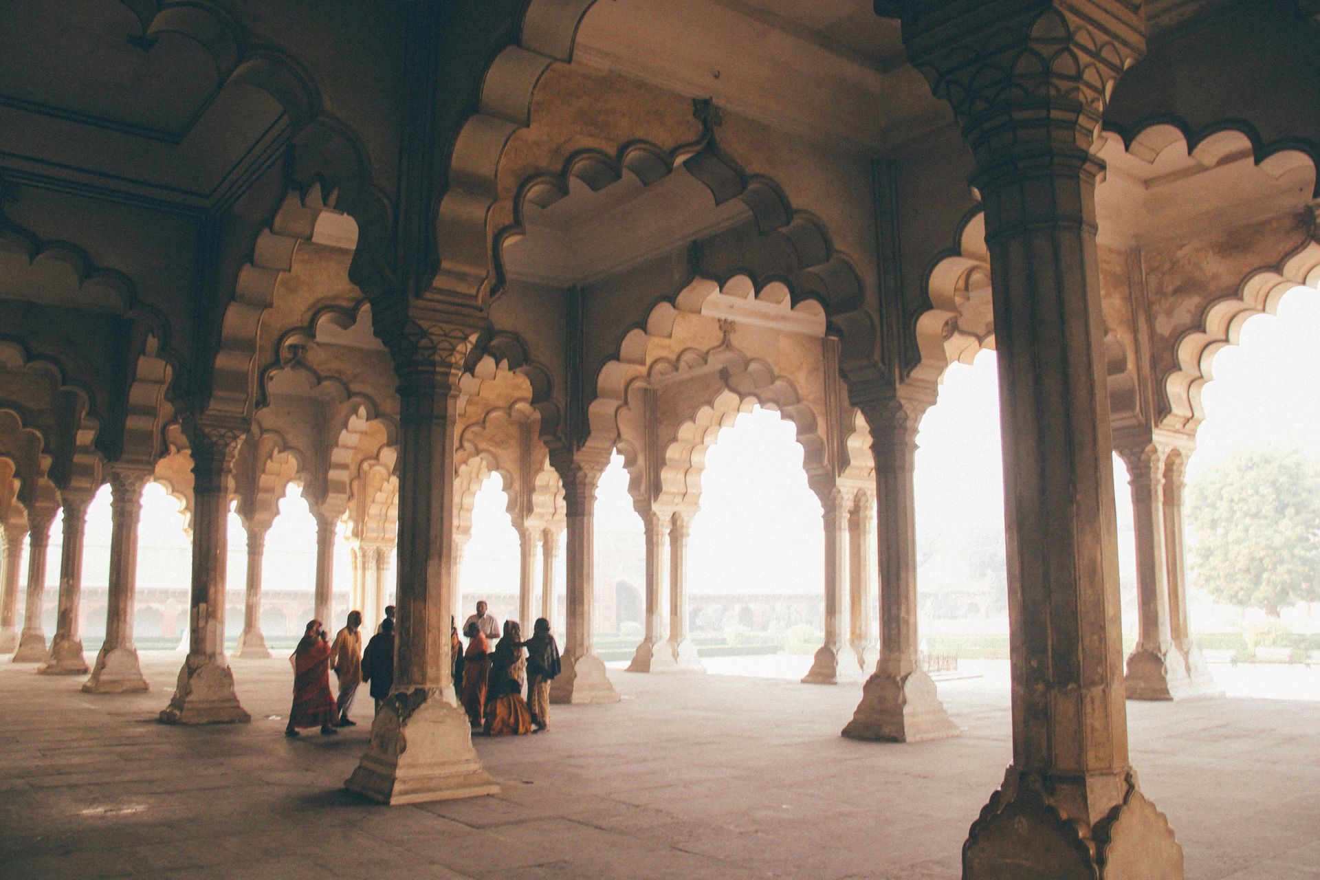 Stone colonnade with arched openings; people in the distance in Agra, India.
