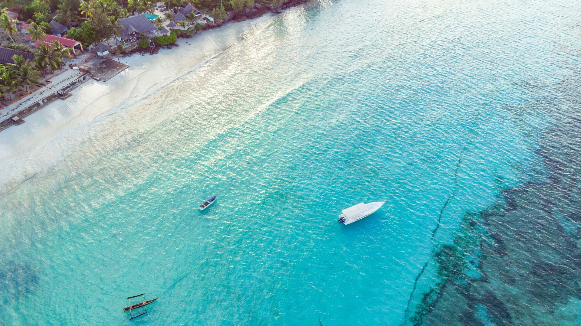 An aerial view of a tropical beach with a boat in the water in Zanzibar, Tanzania.