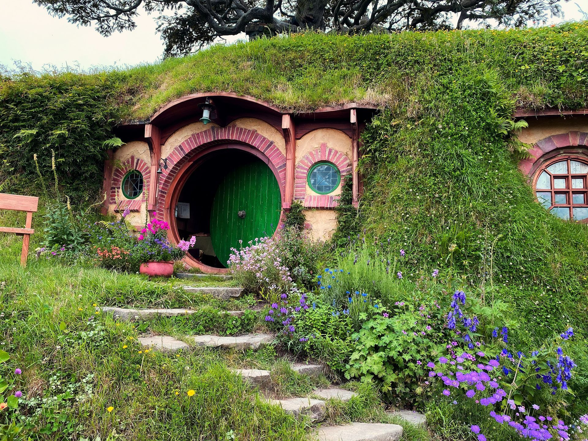 Stairs leading up to a hobbit house surrounded by grass and flowers at the Hobbiton Movie Set in Matamata, New Zealand.