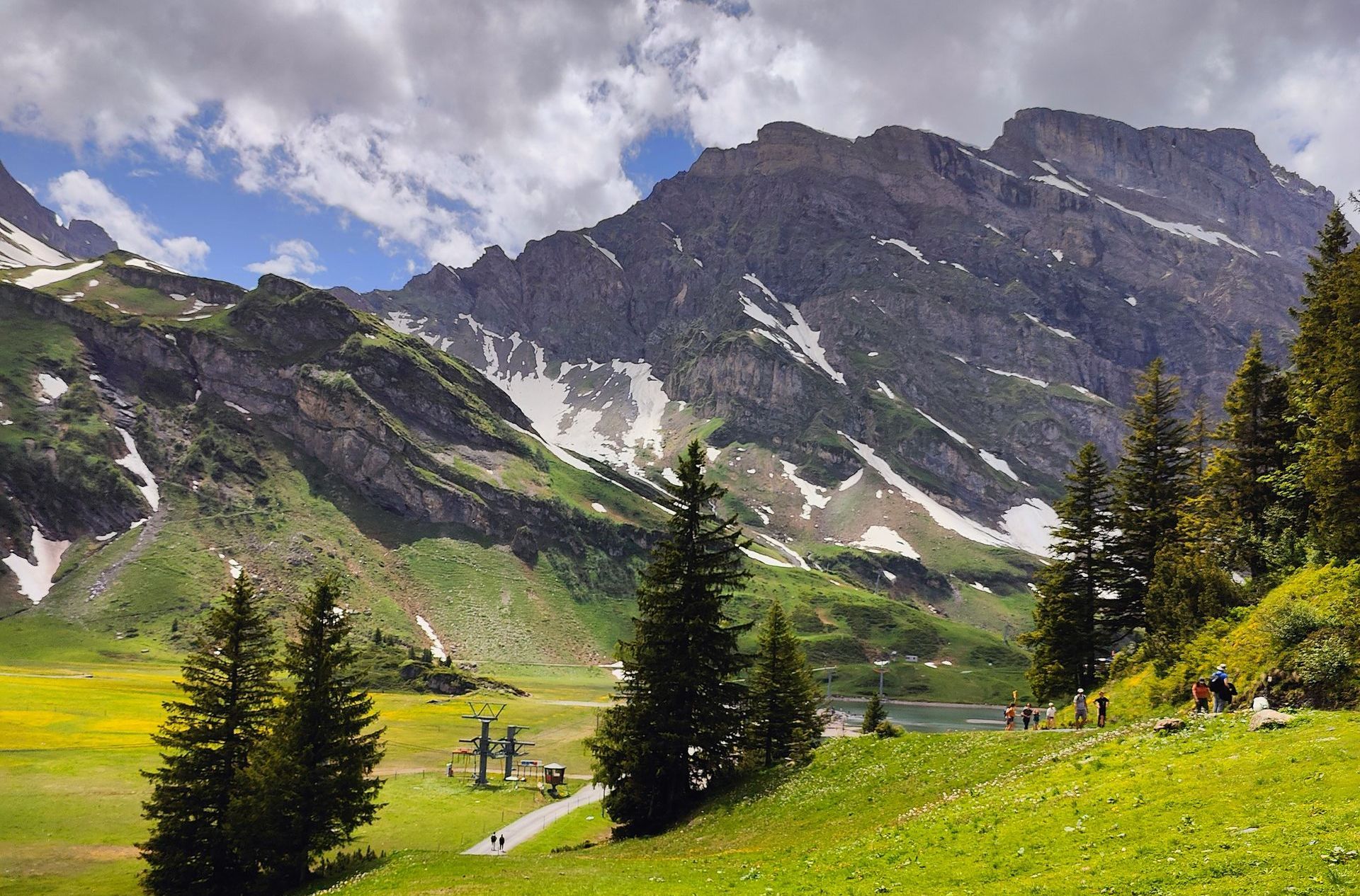 A group of people is walking in the mountains near a lake in Switzerland.