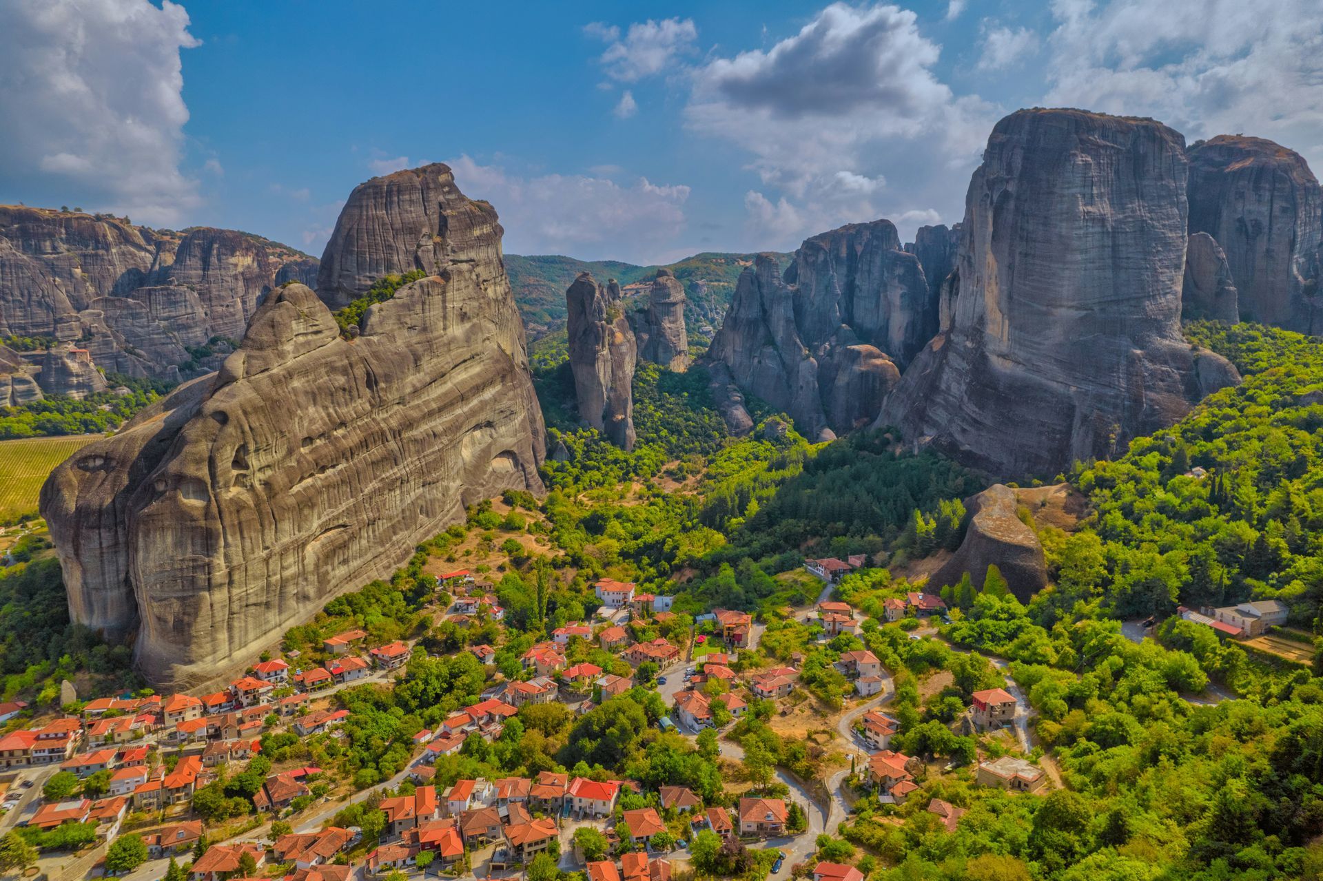 An aerial view of Kalabaka, Greece, surrounded by mountains and trees.