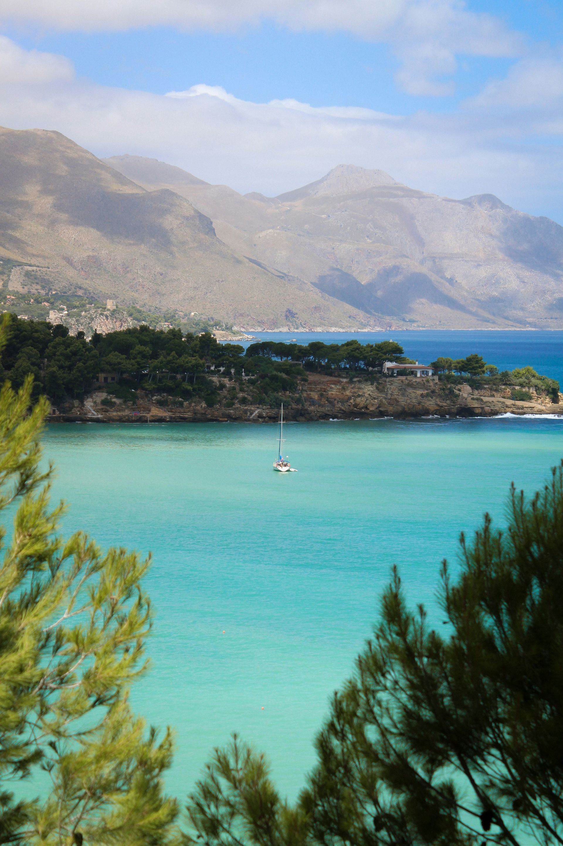 A boat is in the middle of a lake with mountains in the background