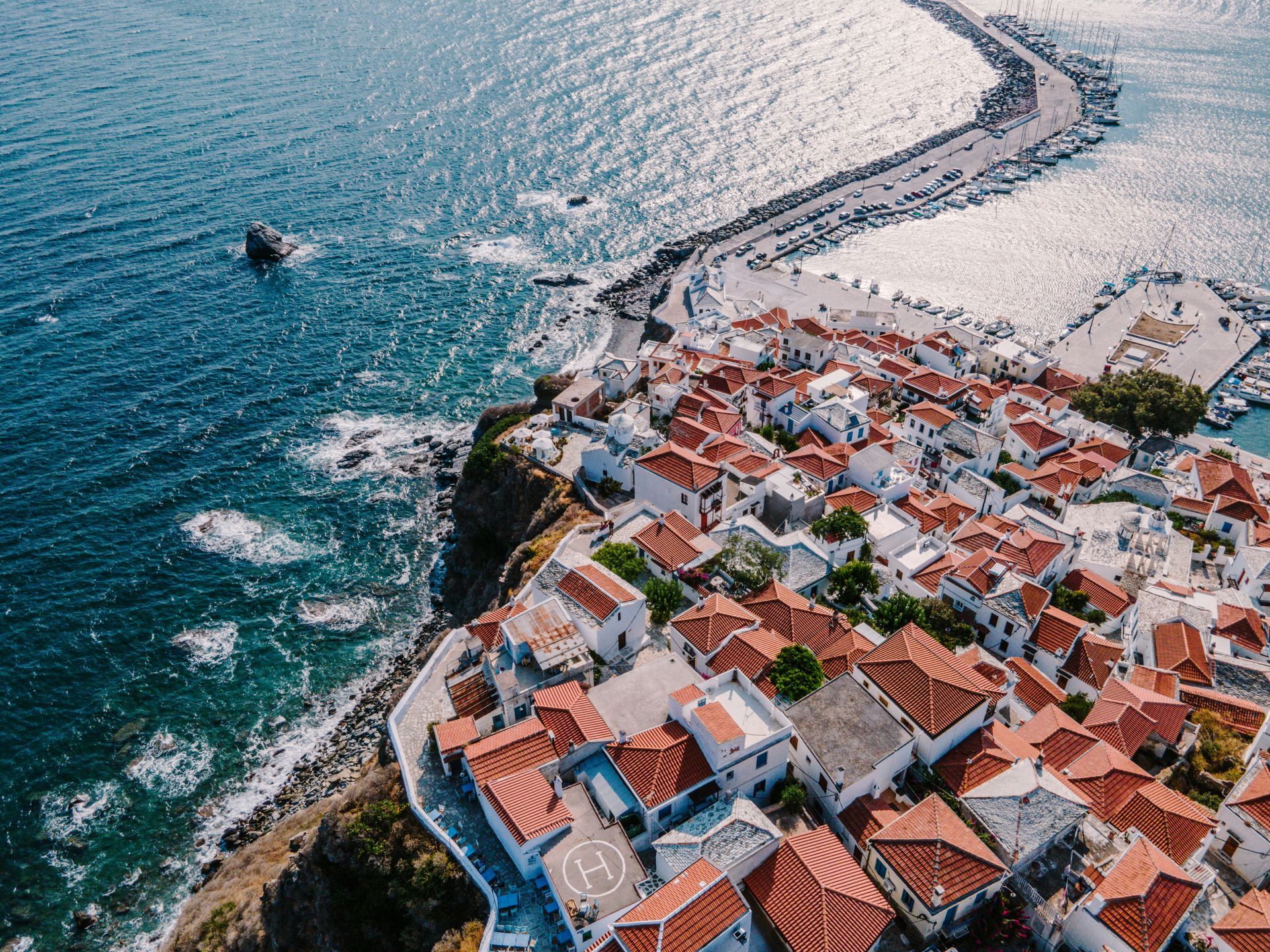 An aerial view of a small town on a cliff overlooking the ocean in Skopelos, Greece.