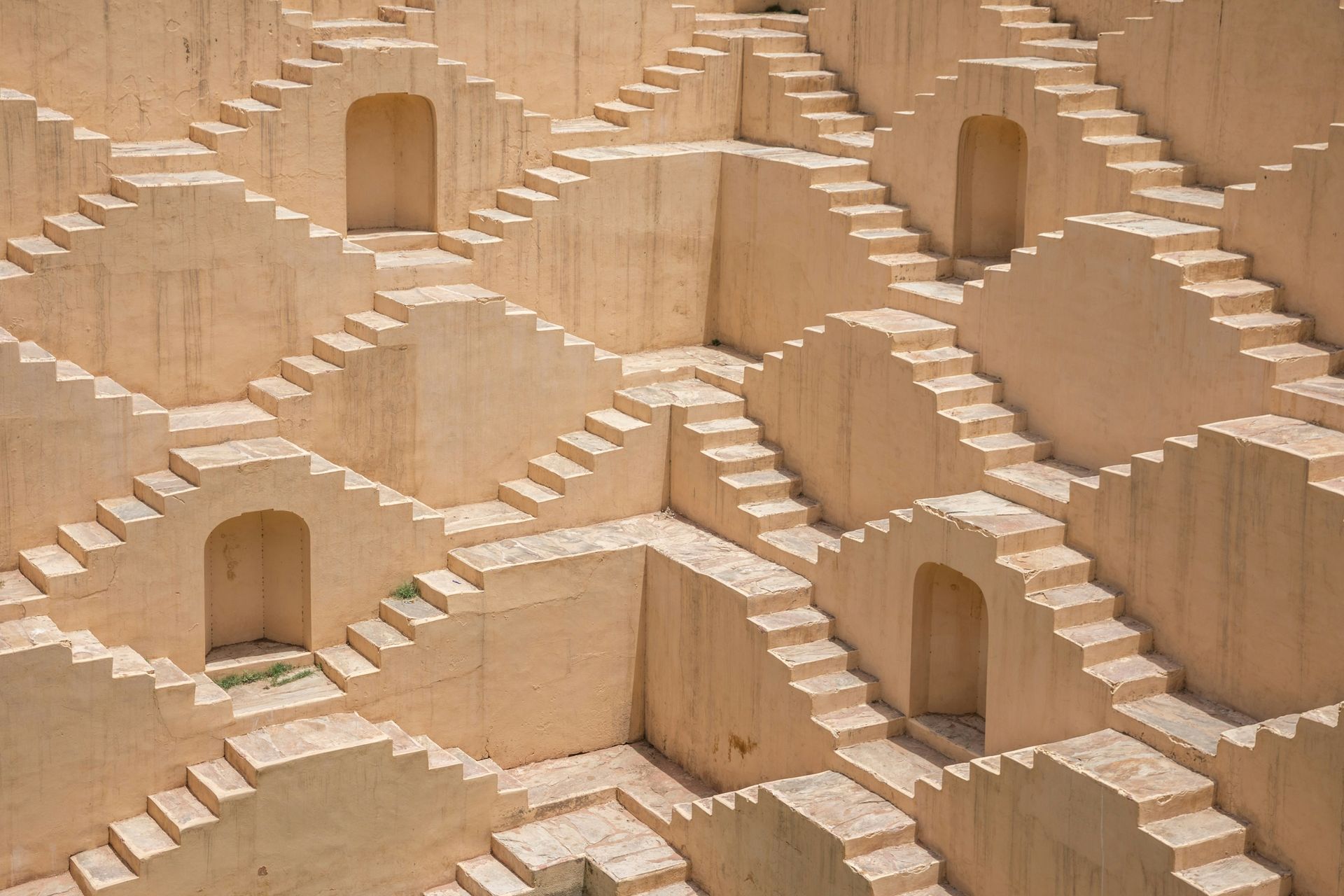 Beige stepwell with intersecting staircases leading downwards in Jaipur, India.