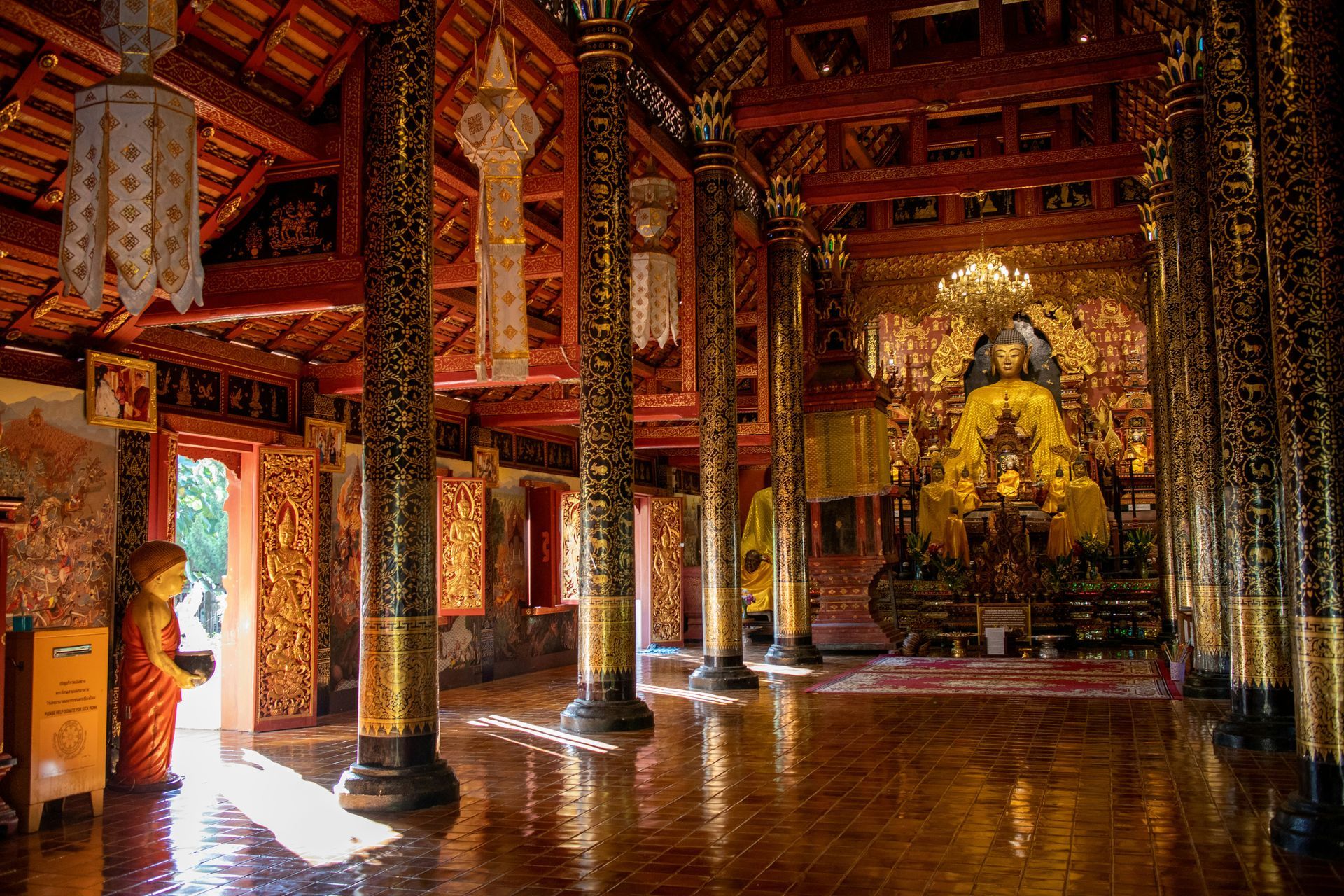 There is a large red and gold temple with a Buddha statue in the middle in Pai, Thailand.