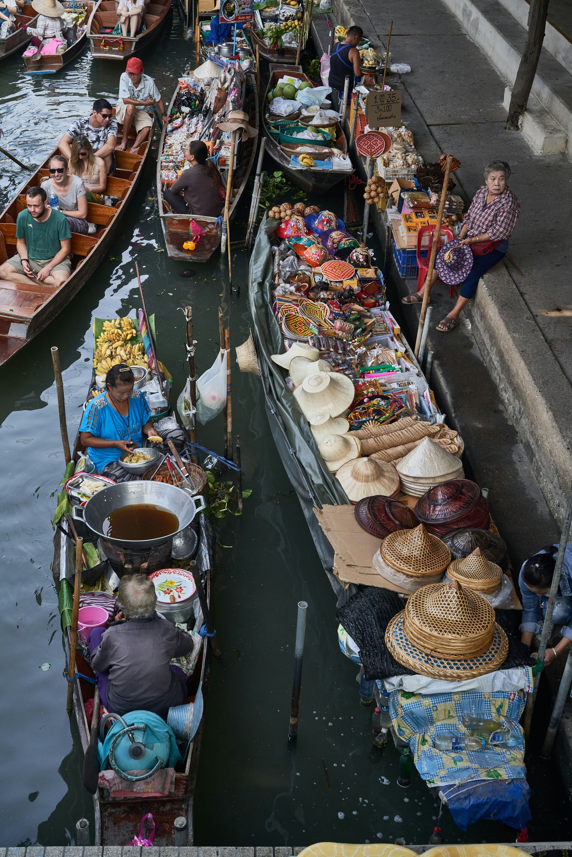 A group of boats filled with food and people are floating down the Damnoen Saduak river market in Thailand.