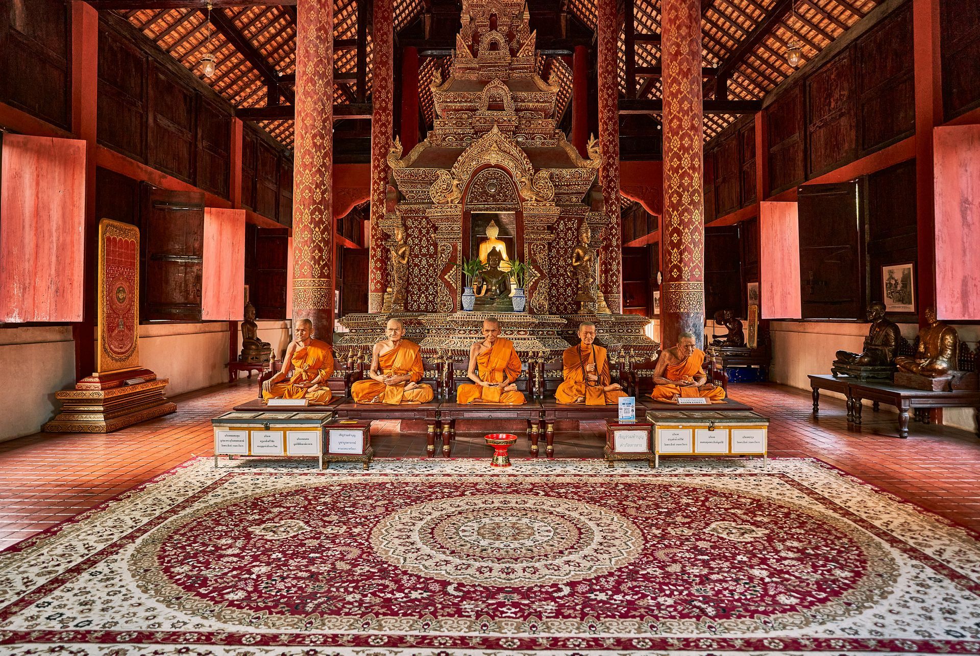 A group of monks are sitting in front of a statue in a temple in Chiang Mai, Thailand.